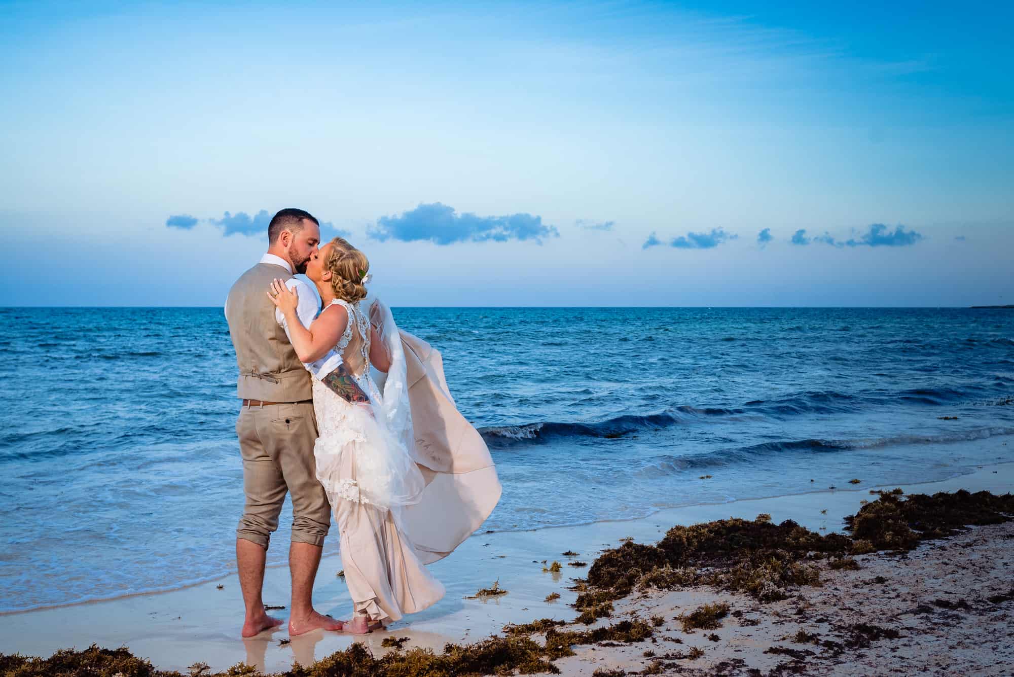 long shot of bride and groom on the beach kissing as one of the Top Wedding Day Poses for the Happy Couple