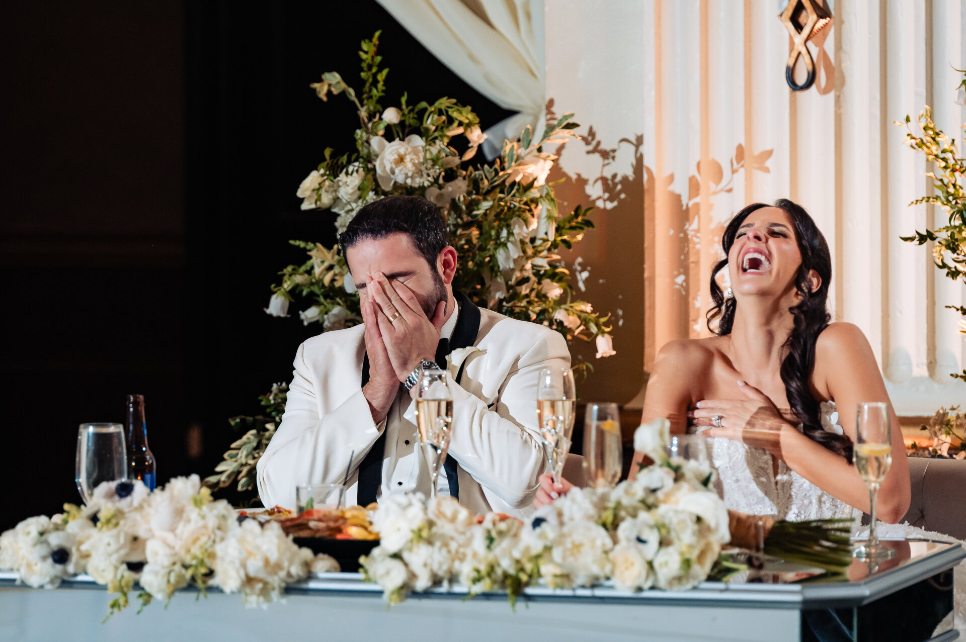 Bride and groom laughing together at the sweetheart table during their wedding reception at The Ben.