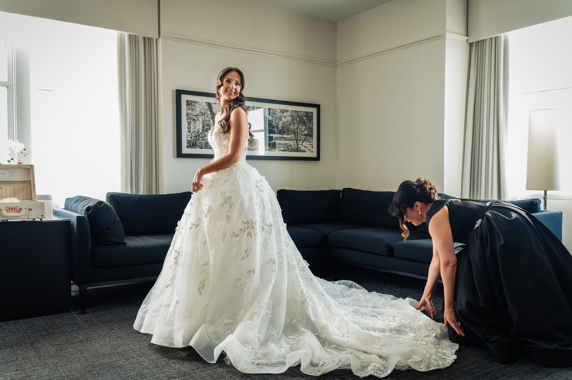 Bride’s mother straightening her daughter’s gown as they prepare for wedding