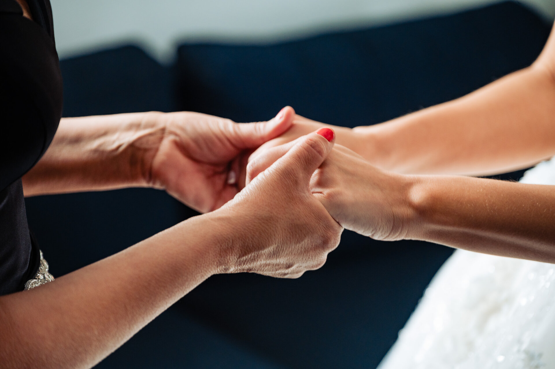 Close-up of the bride’s hand gently holding her mother’s hand, capturing a tender moment of connection and support.