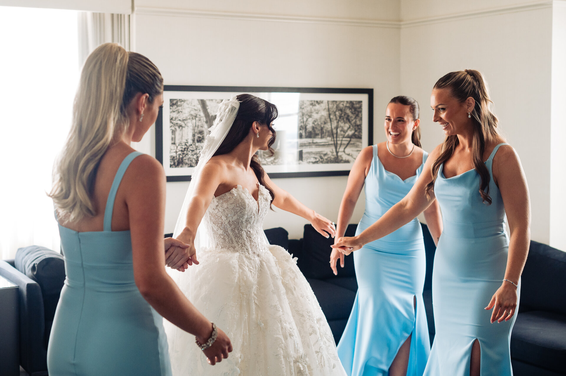Group of bridesmaids surrounding bride, smiling and showing affection