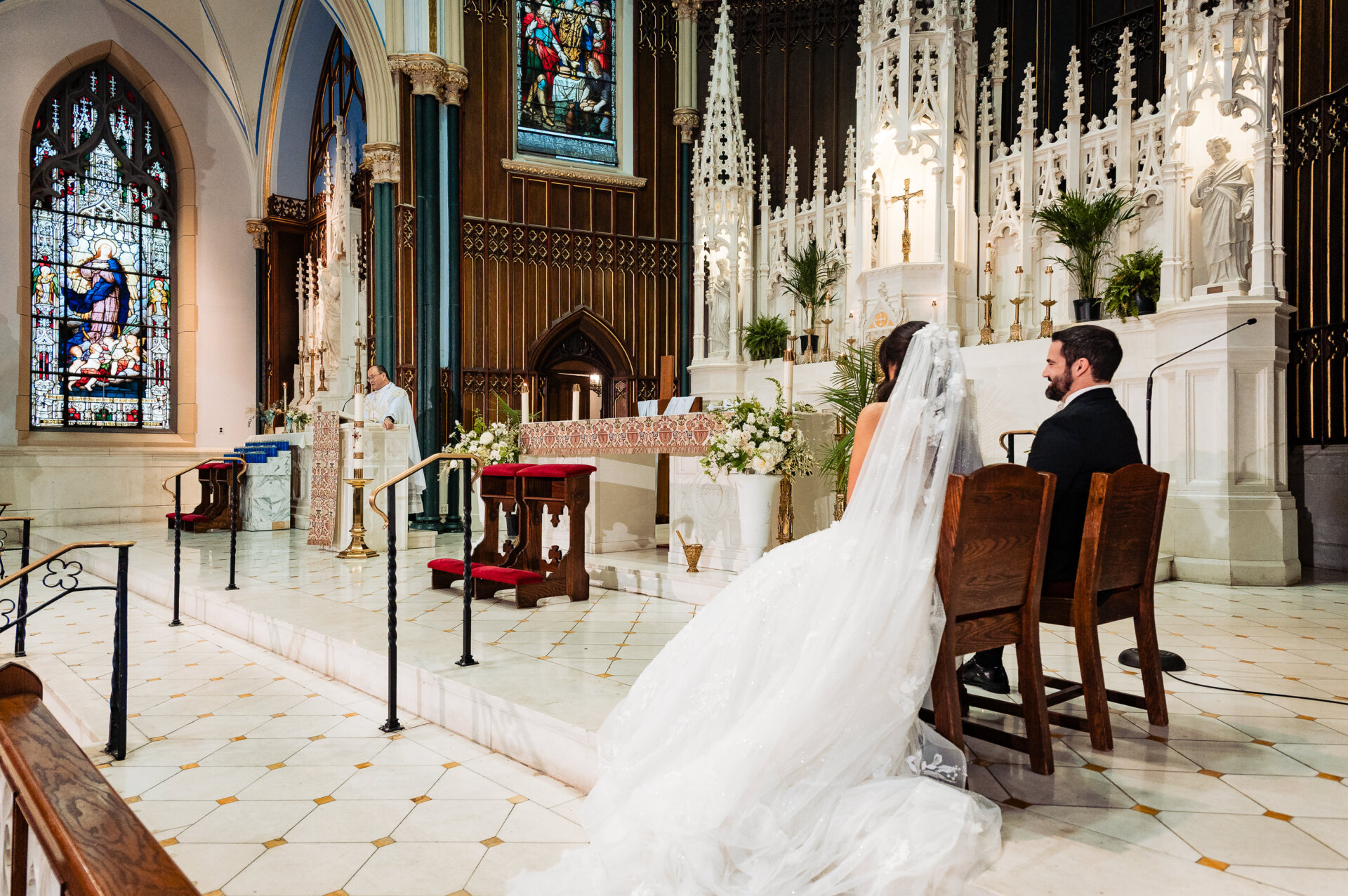 Bride and groom seated beside the altar while listening to the priest