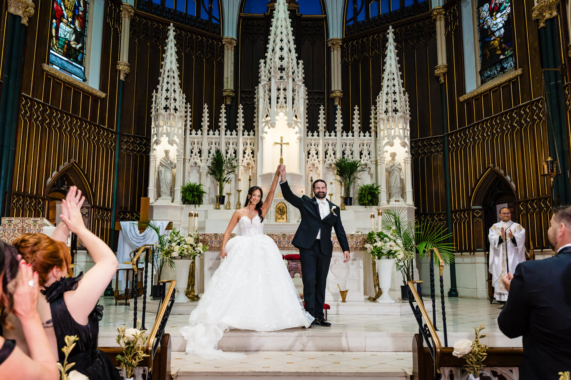 Newly pronounced couple standing at the altar, raising their hands together in celebration after the ceremony.