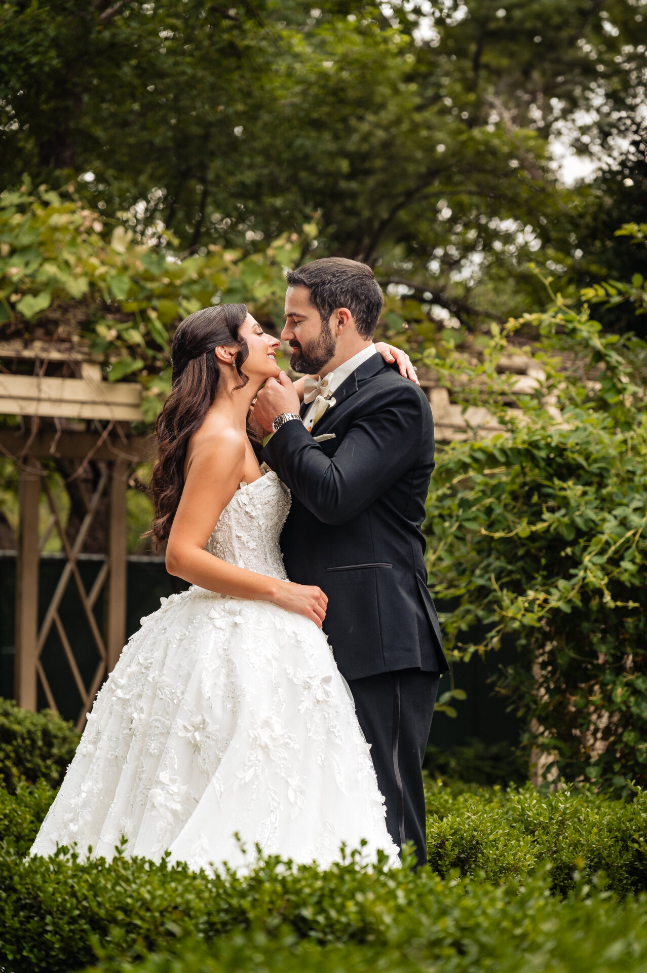 Newly pronounced husband and wife share an intimate kiss in the garden before their wedding reception.