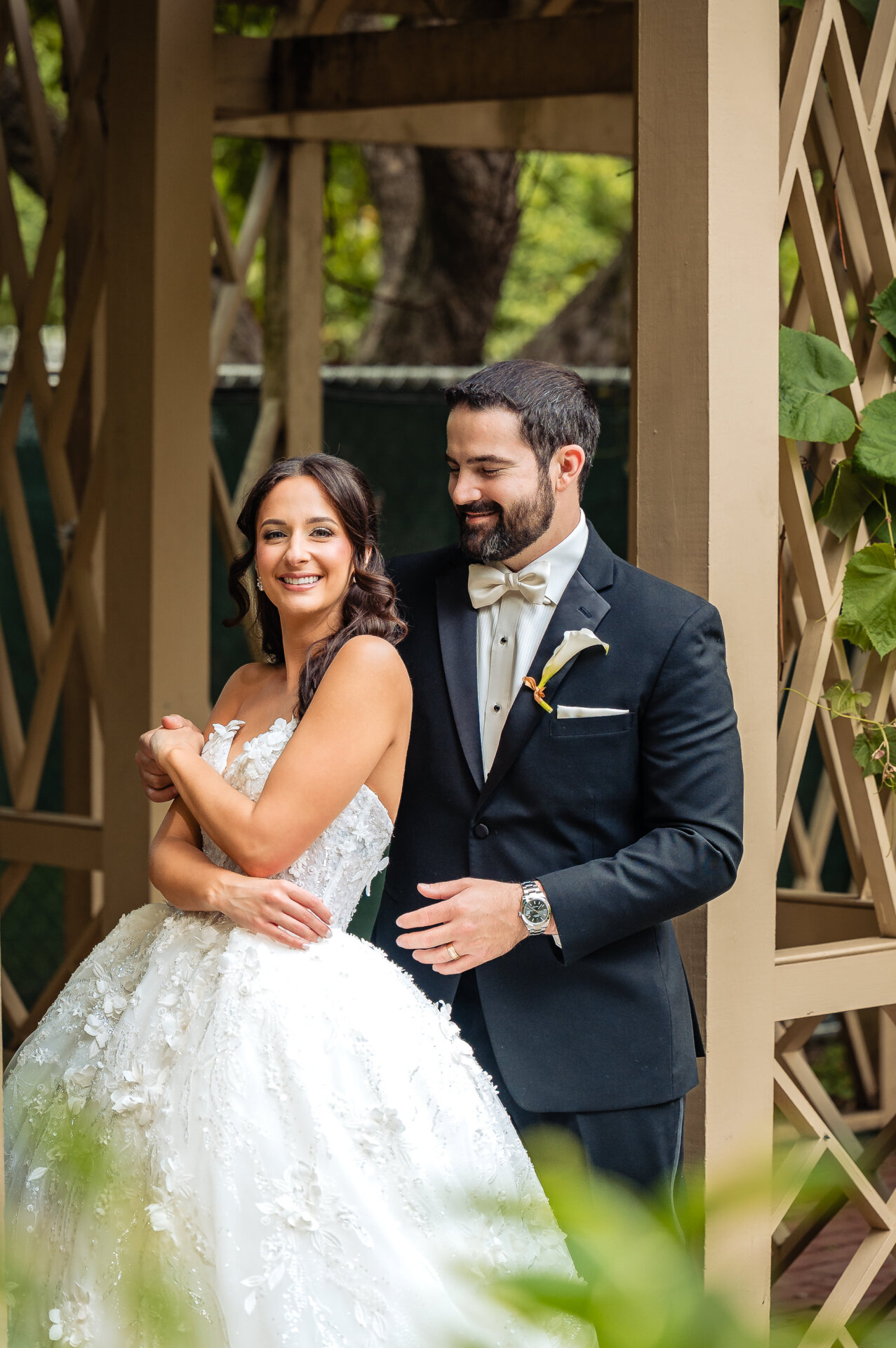 Newly pronounced husband and wife having a light-hearted moment while taking a pose in the garden.