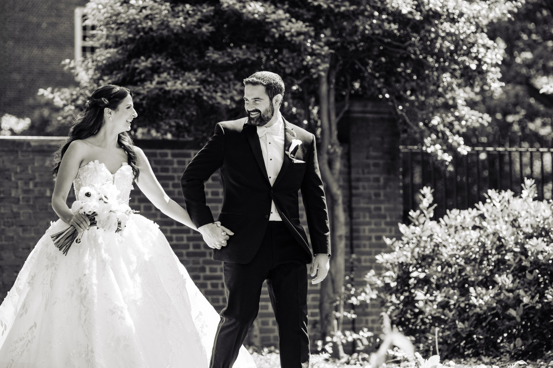 Black and white image of the newlyweds walking together in the garden after the ceremony.