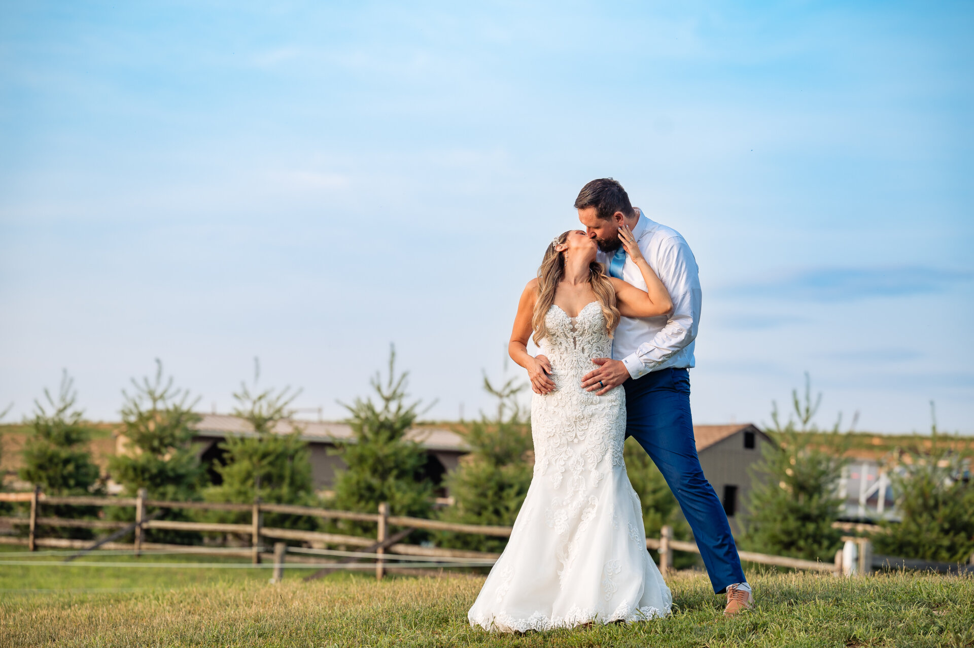 Bride and groom sharing an intimate kiss during outdoor countryside wedding portraits.