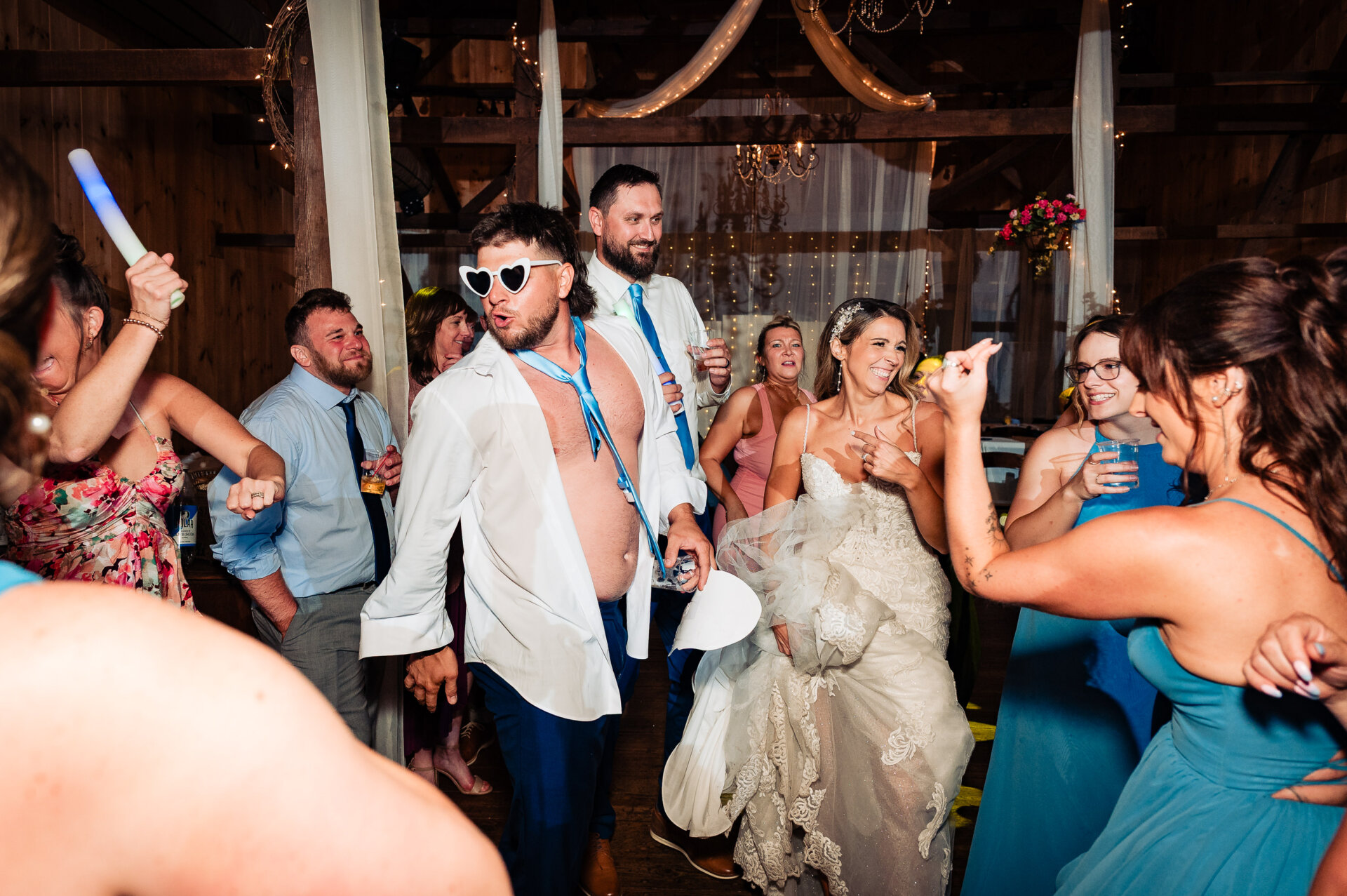 Bride dancing with friends while holding playful dog-face props and glow sticks at the reception