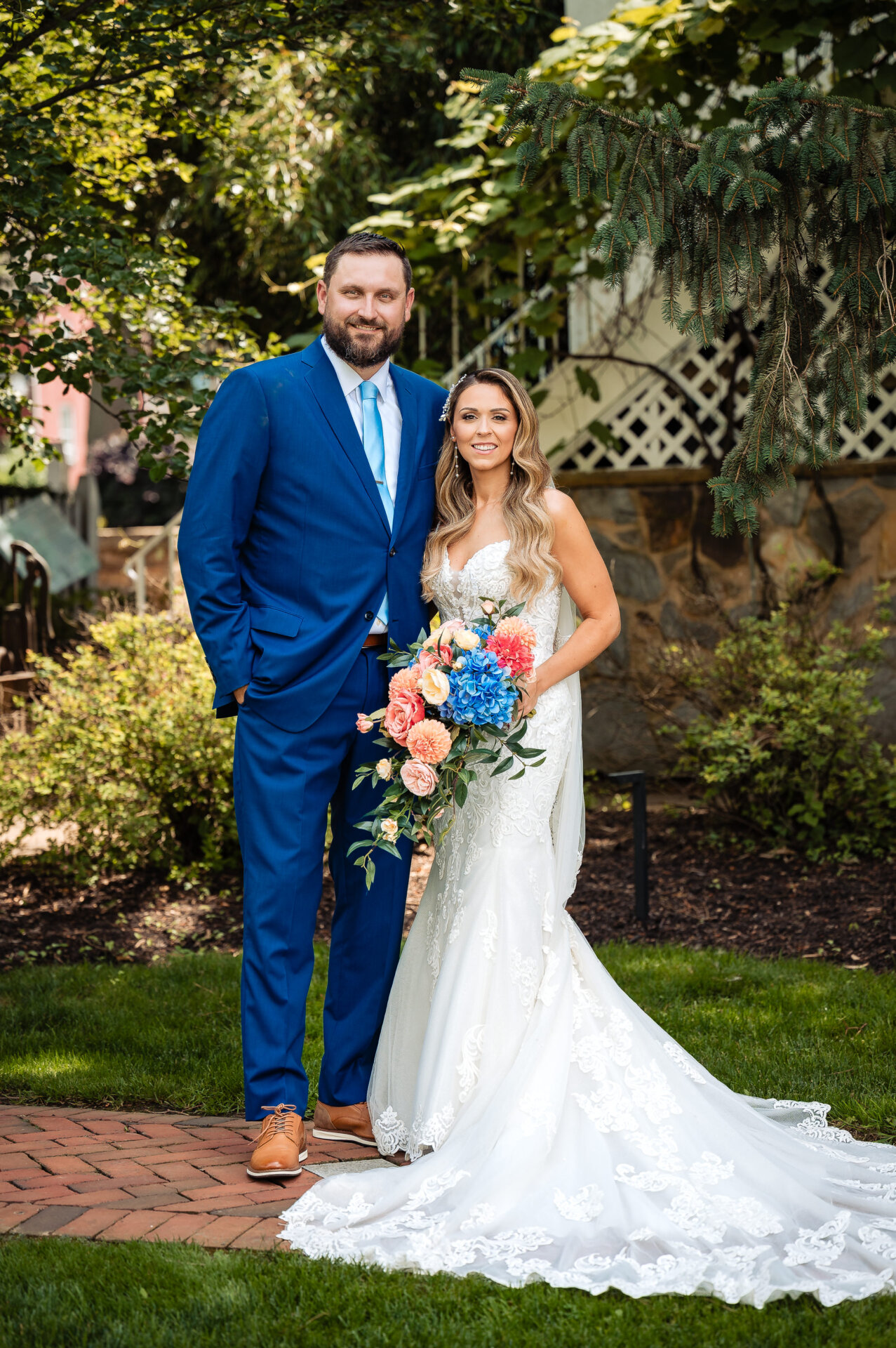 Bride and groom standing beneath a leafy garden arch during outdoor wedding portraits.