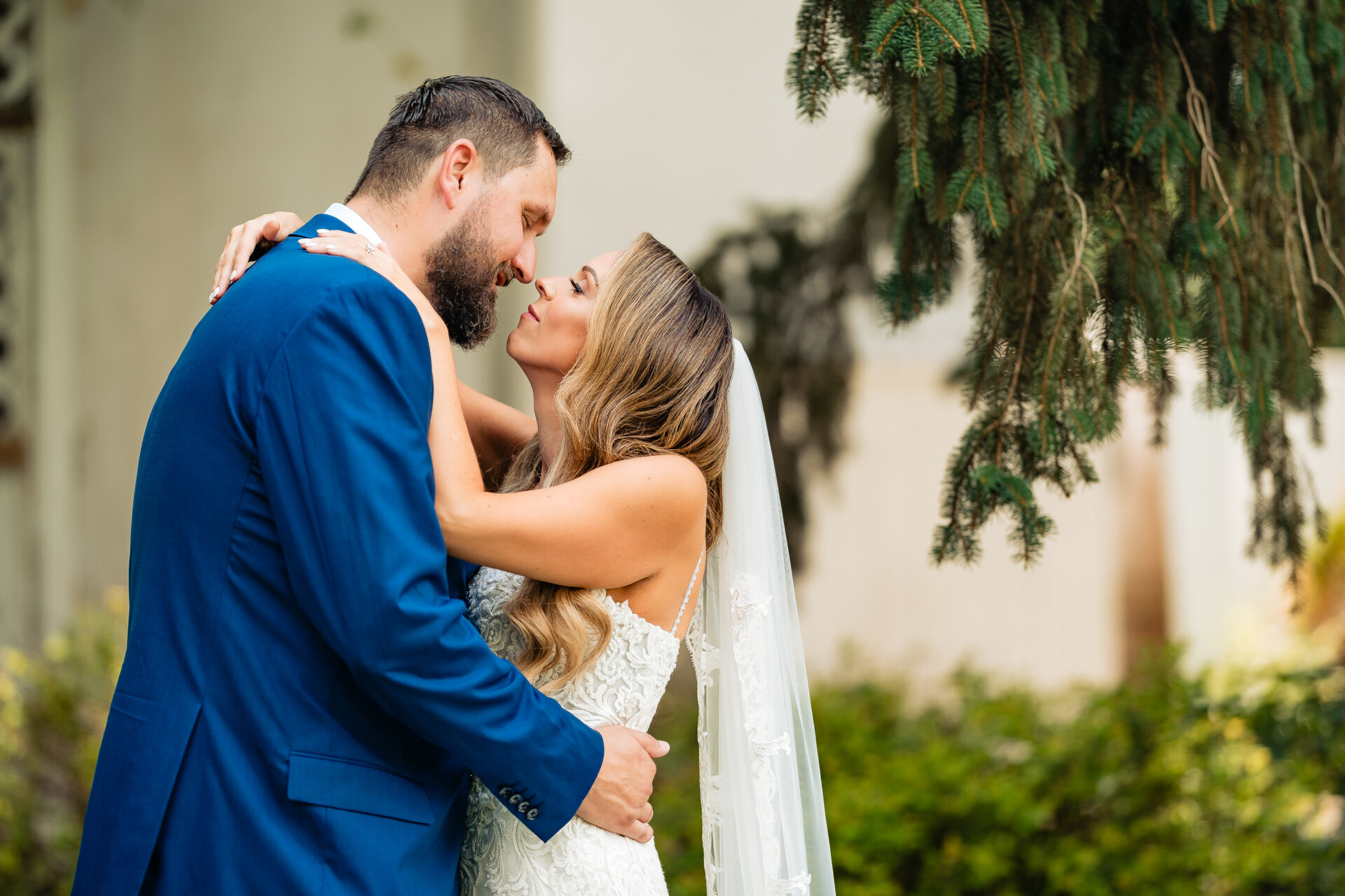Bride and groom sharing an intimate embrace beneath trees after the ceremony