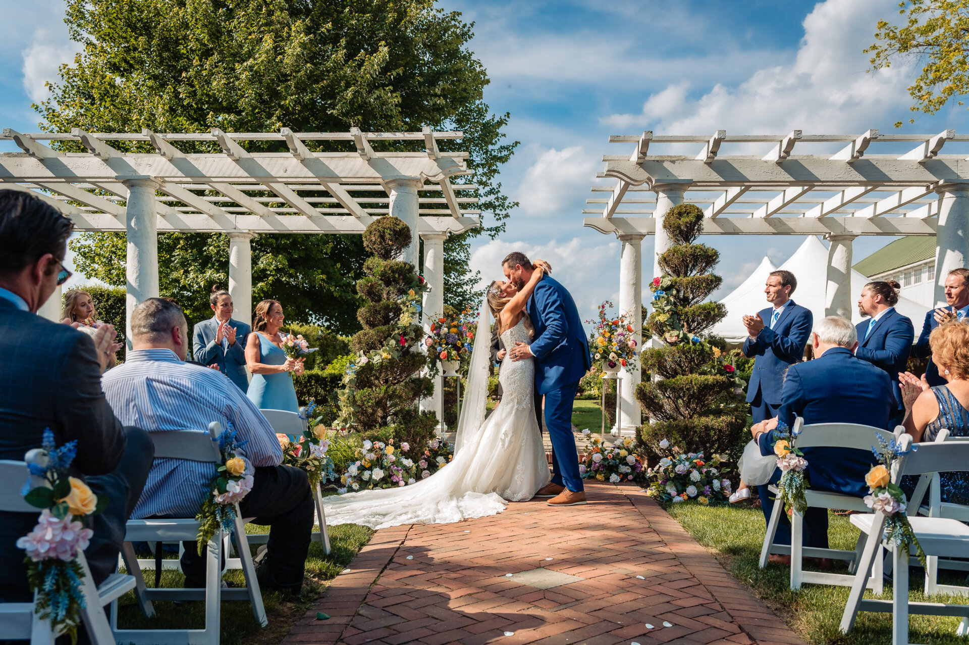 Newly married couple share a kiss while walking down the aisle after their outdoor ceremony.