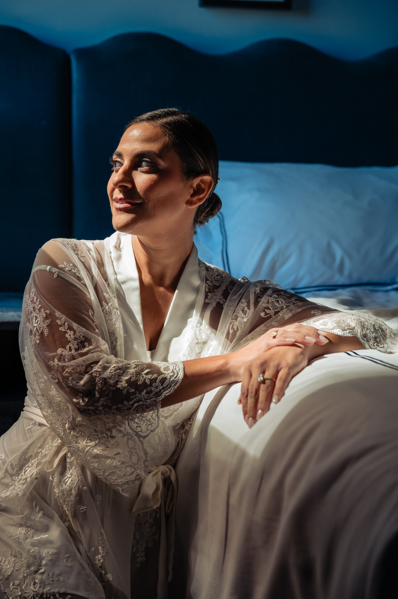 Bride seated in a lace robe during wedding morning preparations