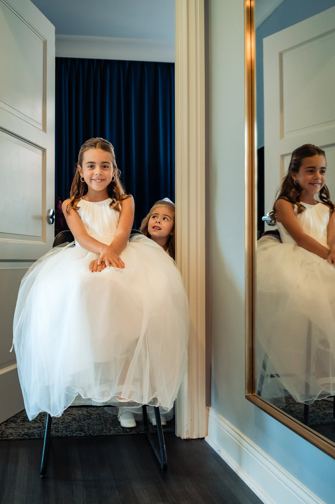 Flower girls sitting together in white dresses during wedding preparations