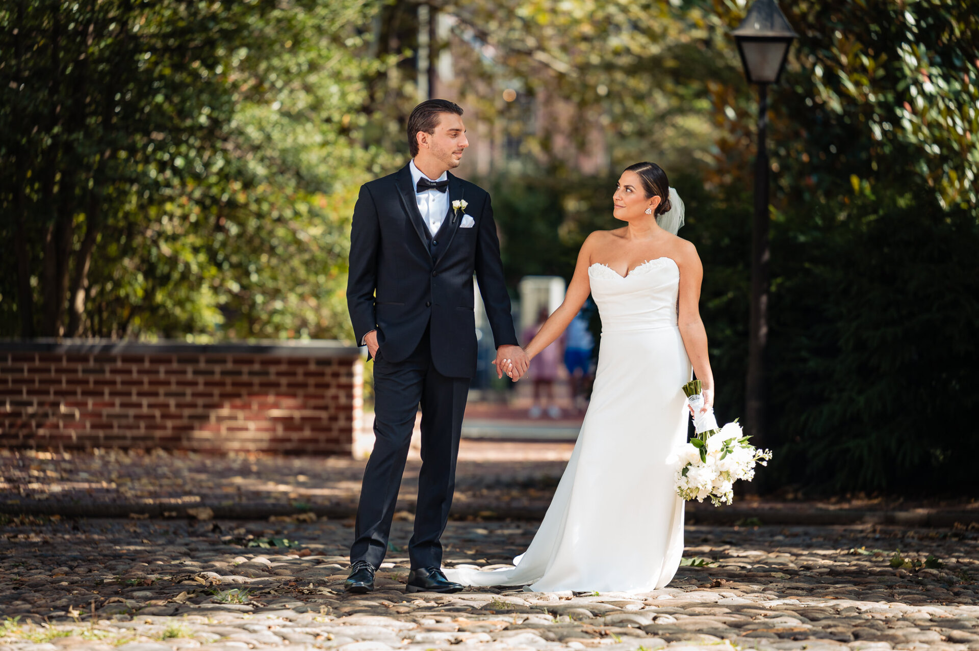 Newlyweds walking in garden with vibrant white mums as they proceed to their wedding venue