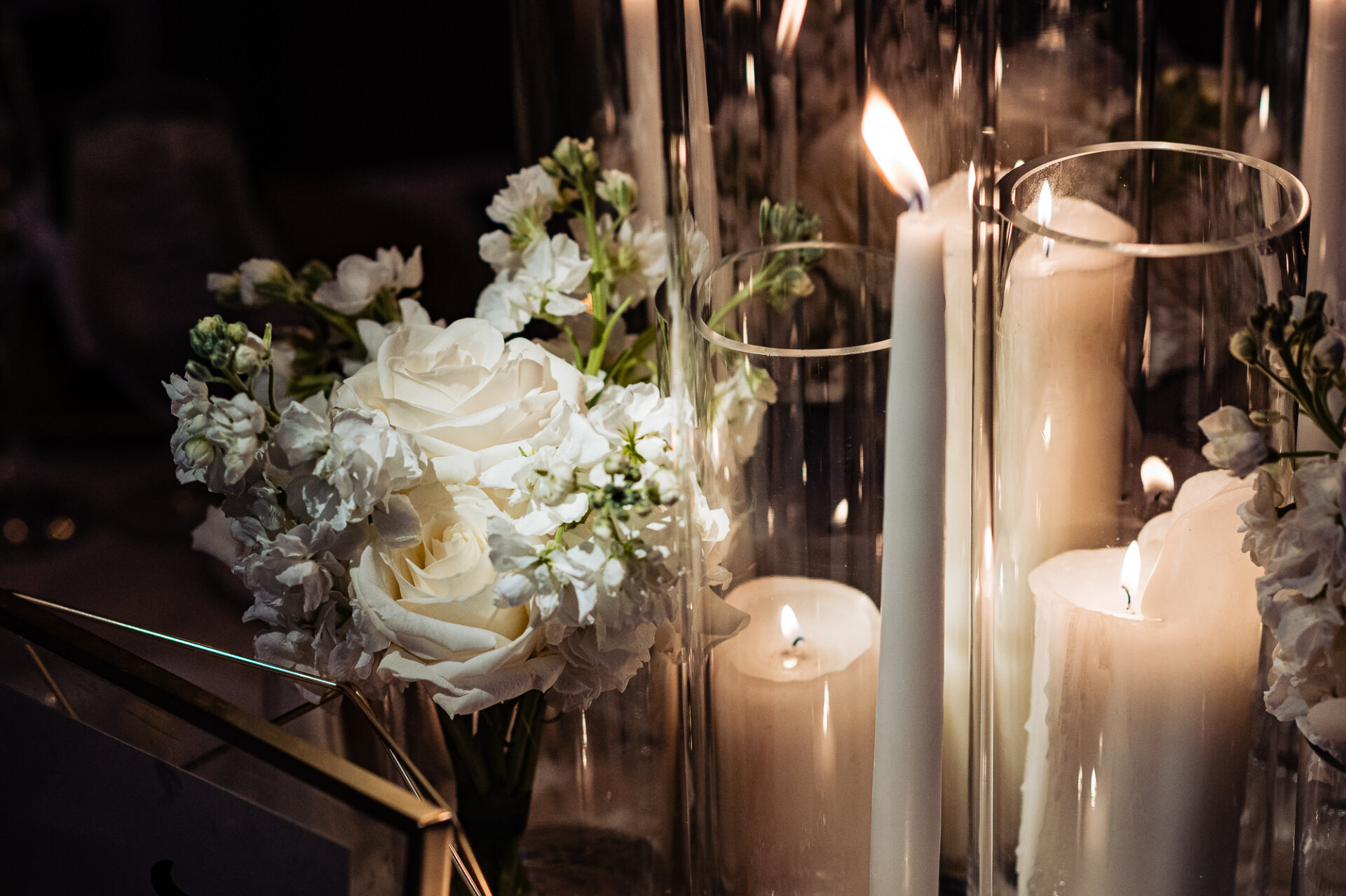 White roses and pillar candles in glass holders