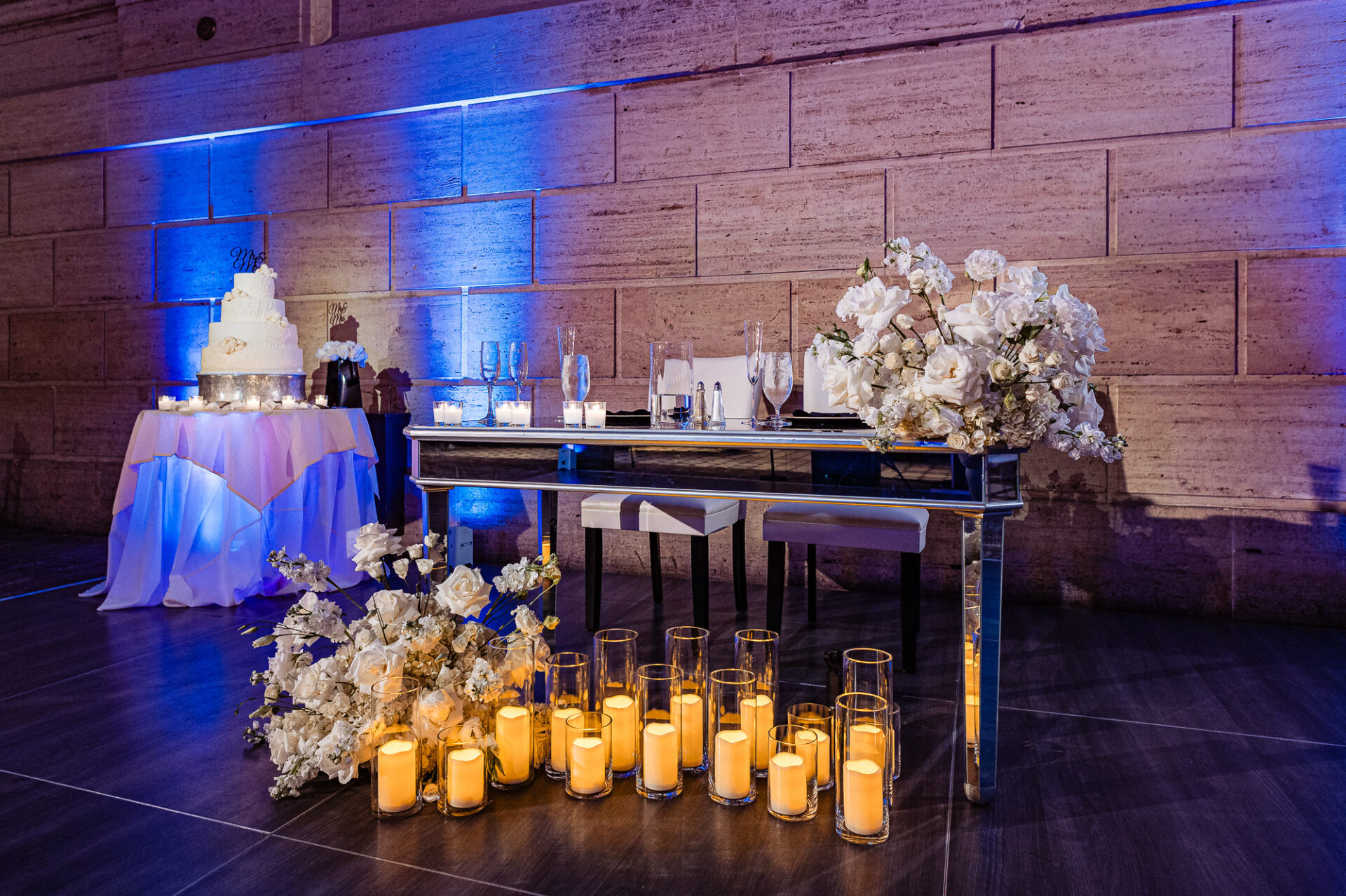 Wedding sweetheart table with white florals, candles, and cake