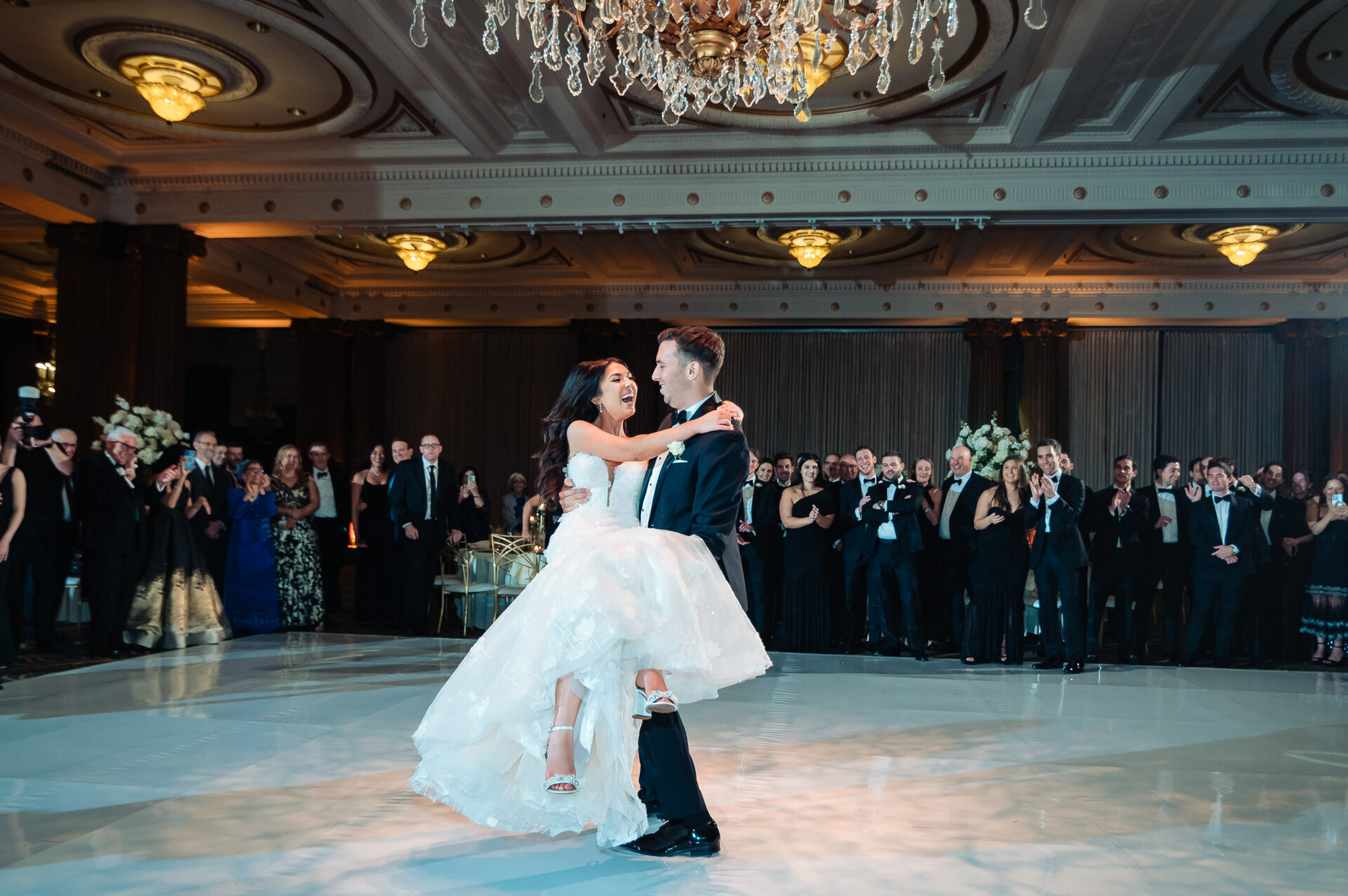 Bride and groom sharing their first dance beneath a grand chandelier in the Crystal Tea Room ballroom