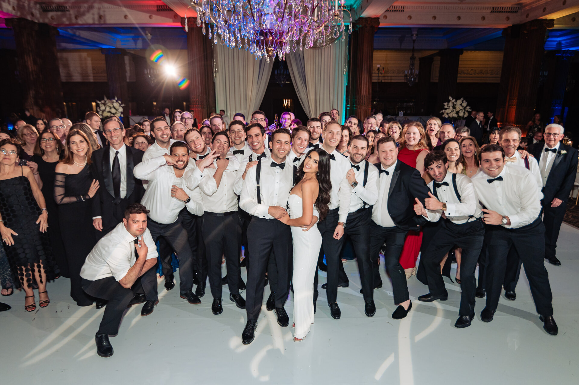 Large group wedding photo on the dance floor with the bride and groom surrounded by guests