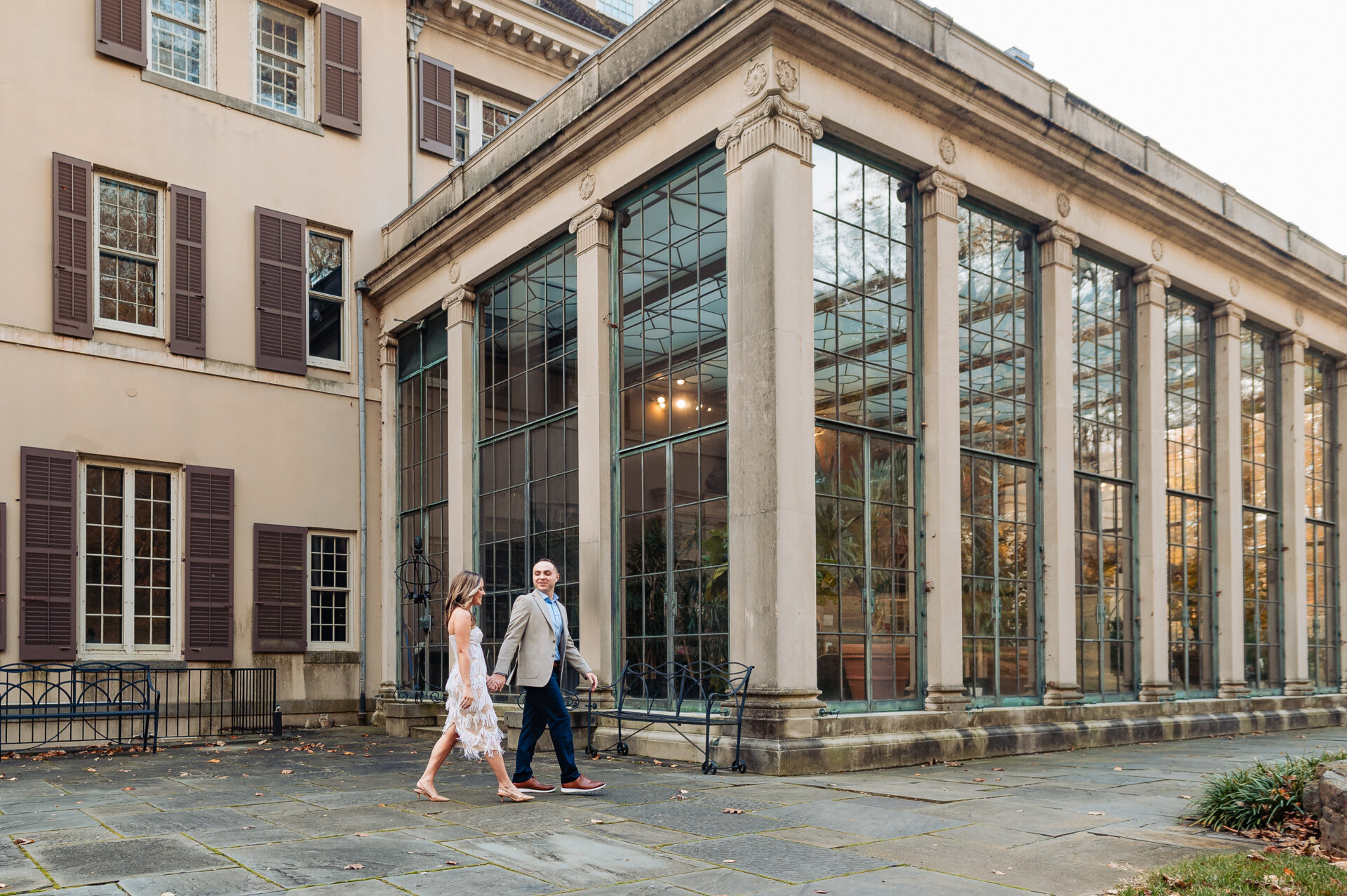 Couple walking past the Winterthur greenhouse during engagement session