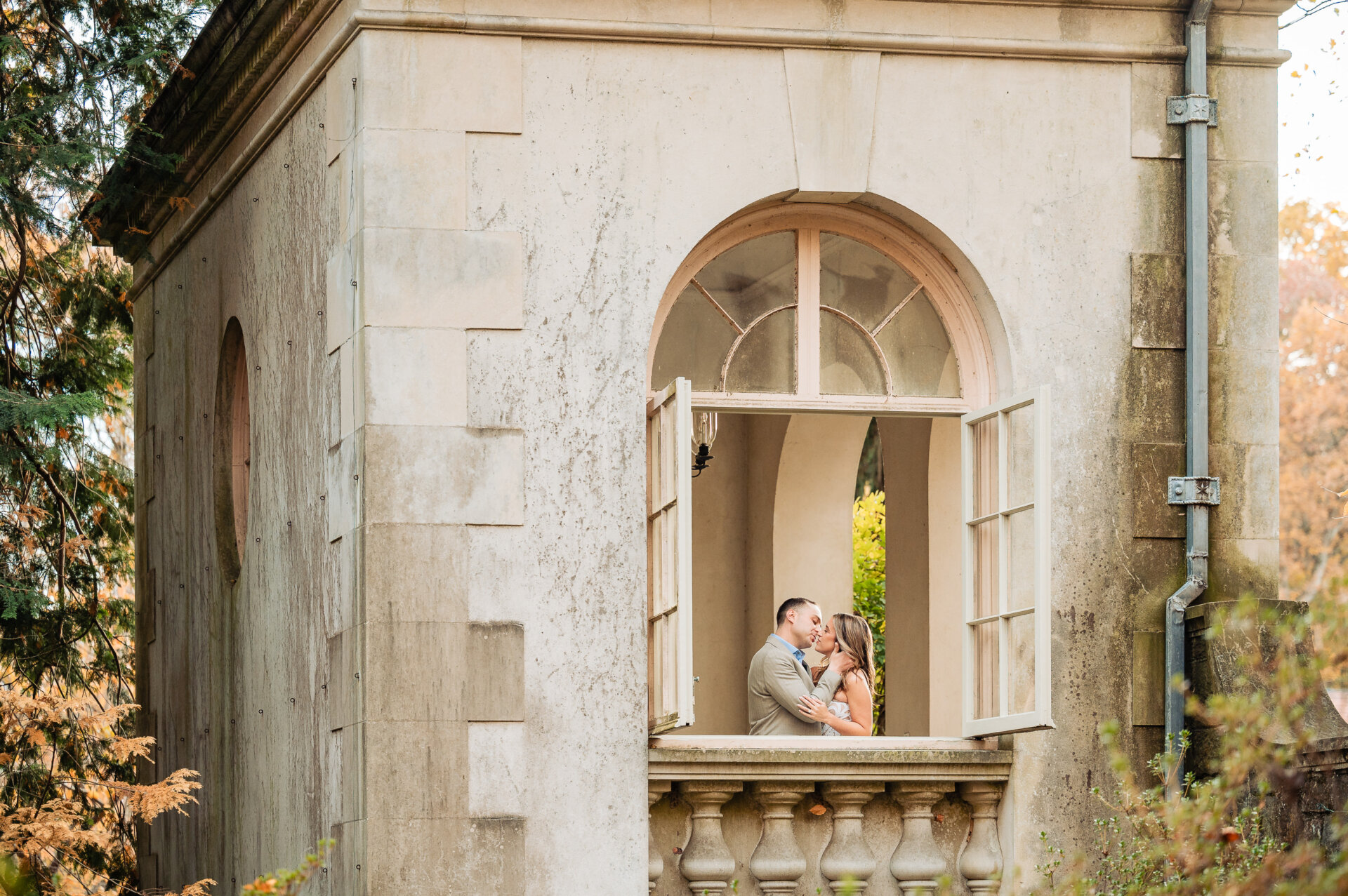 Couple kissing through an arched stone window at Winterthur