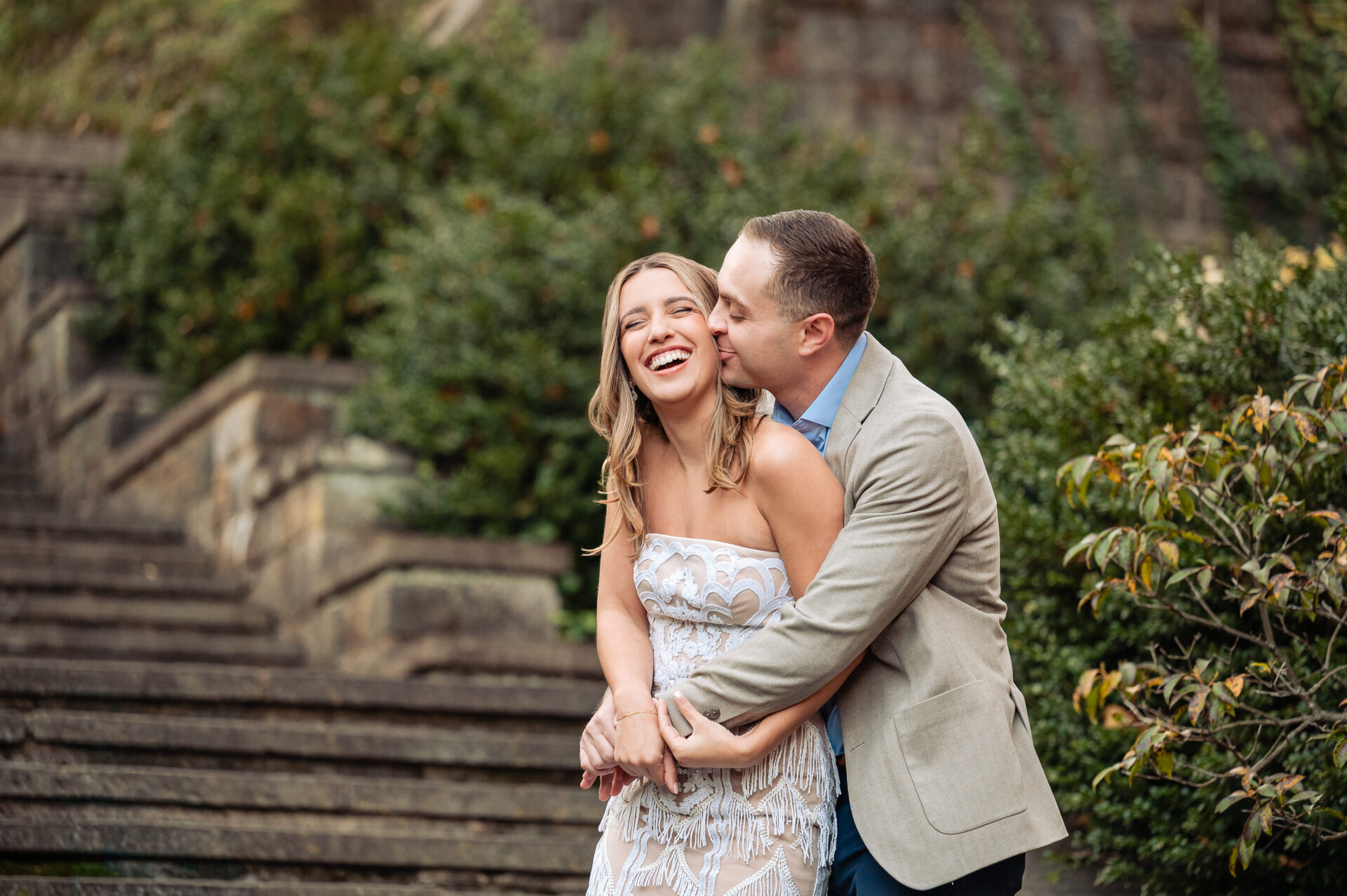 Playful engagement portrait of a couple laughing on stone steps at Winterthur.
