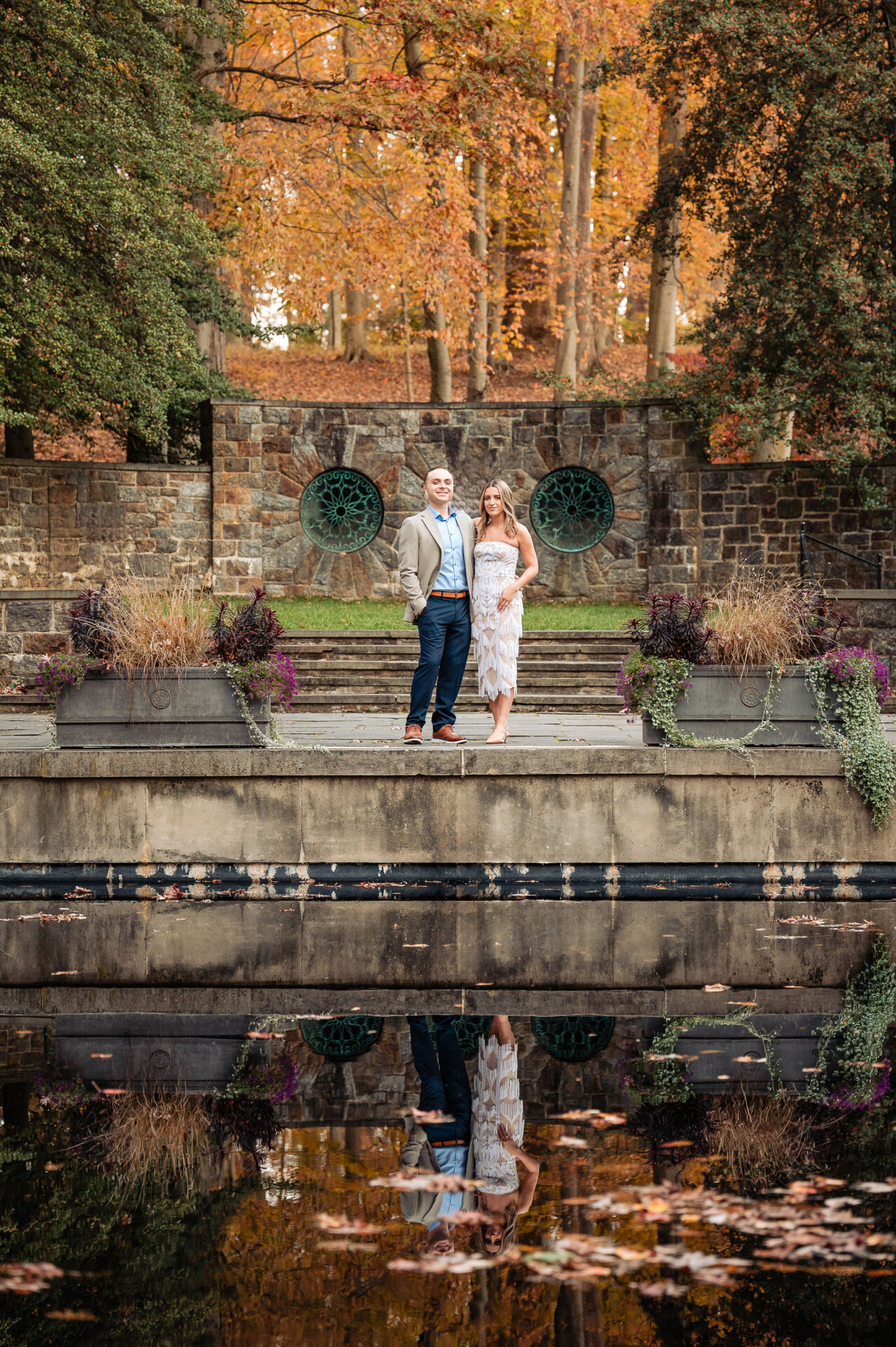 Couple standing by a reflective water feature during their Winterthur engagement shoot.
