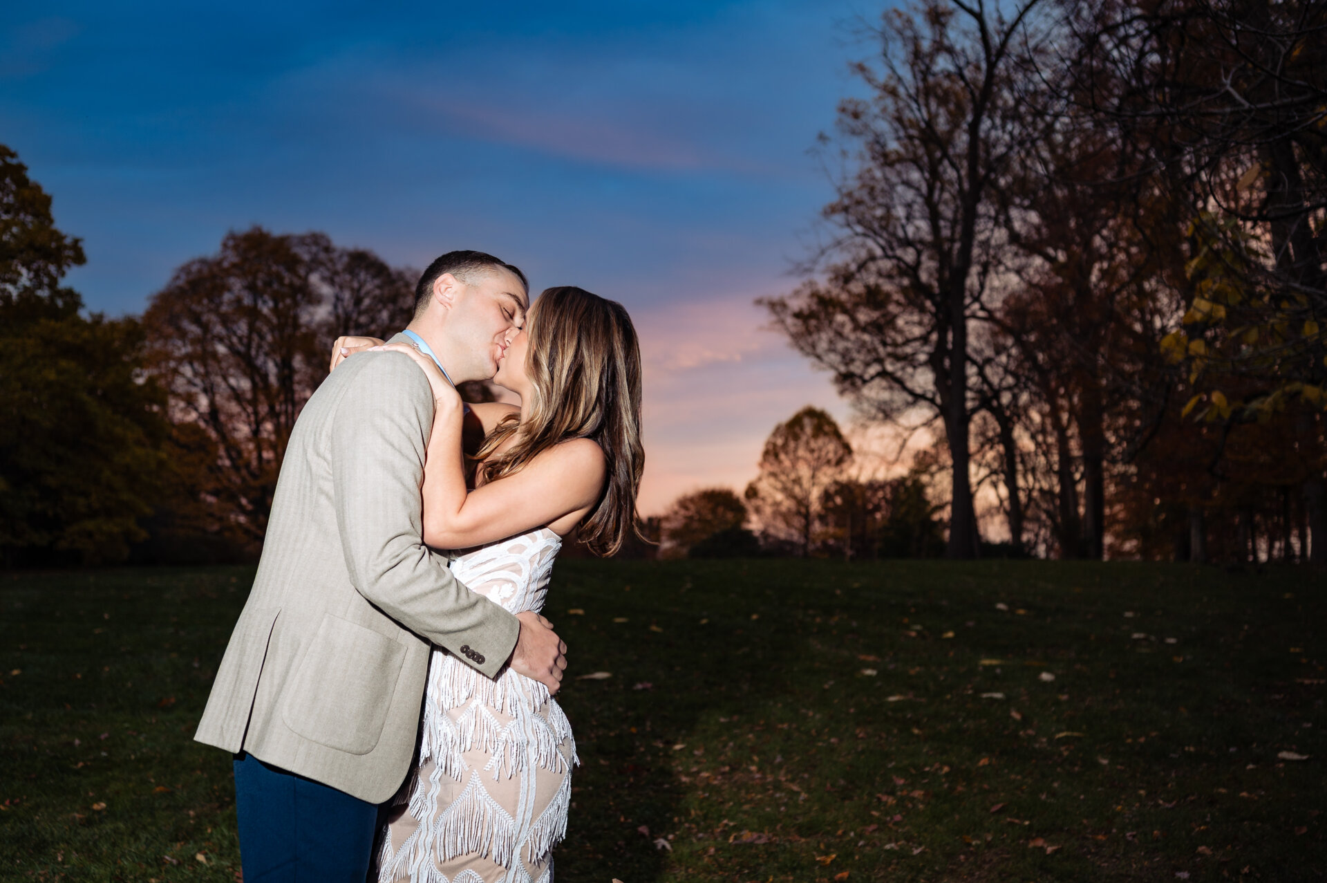 Couple kissing at dusk in an open field during engagement session
