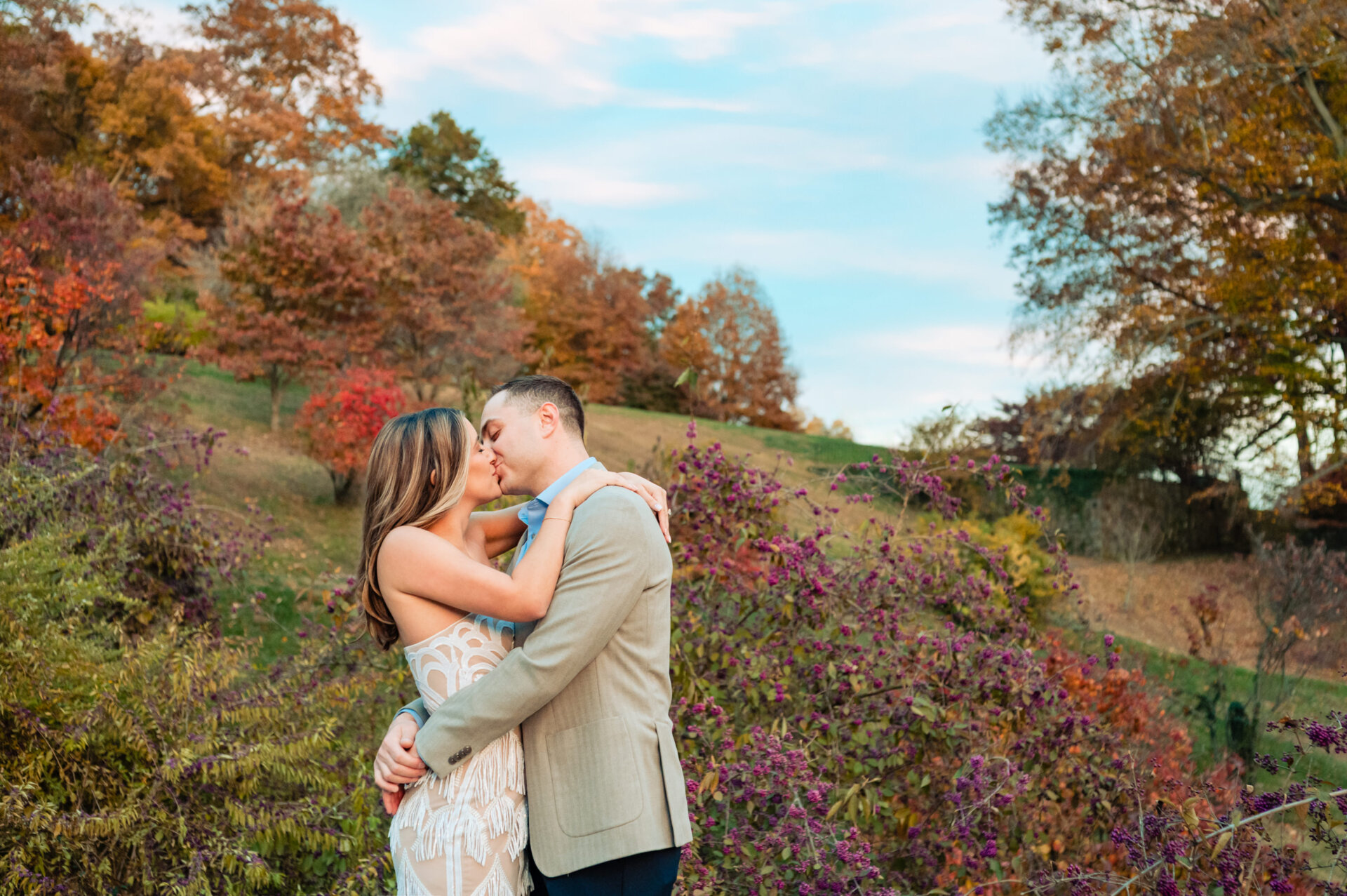 Couple embracing and smiling during an autumn engagement session at Winterthur.