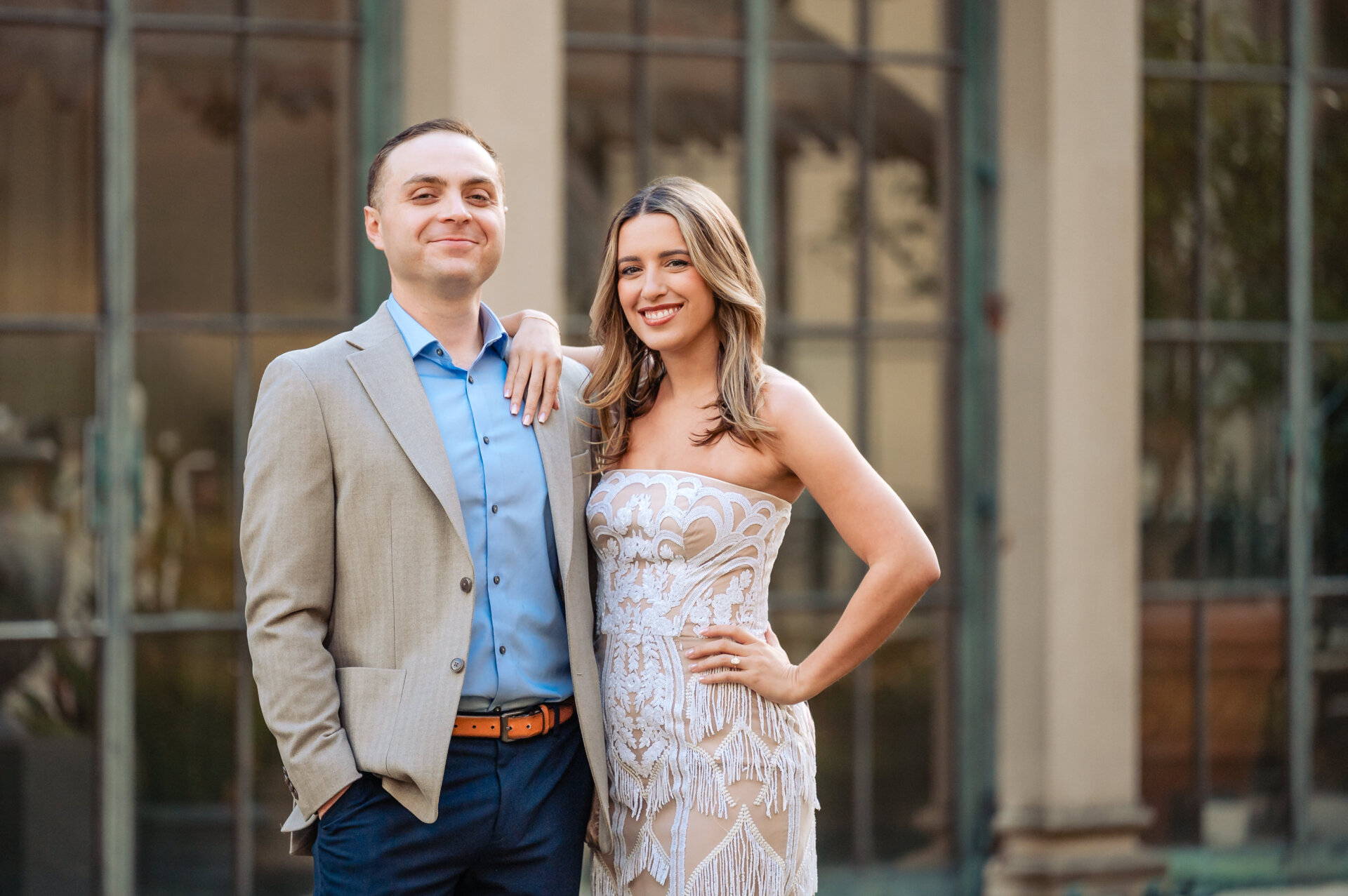 Portrait of an engaged couple smiling in front of a conservatory