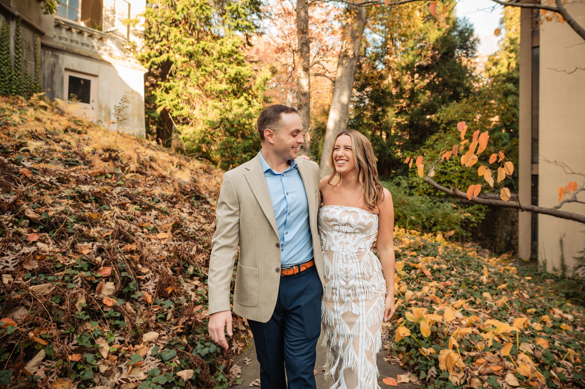 Engaged couple walking together through fall foliage at Winterthur Gardens.