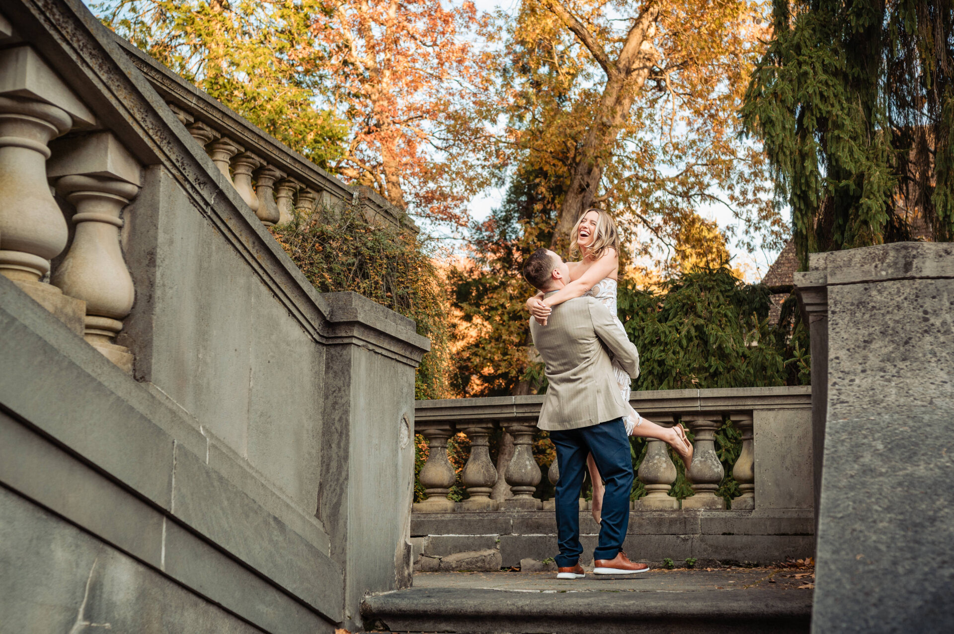 Couple embracing on stone steps framed by fall colors