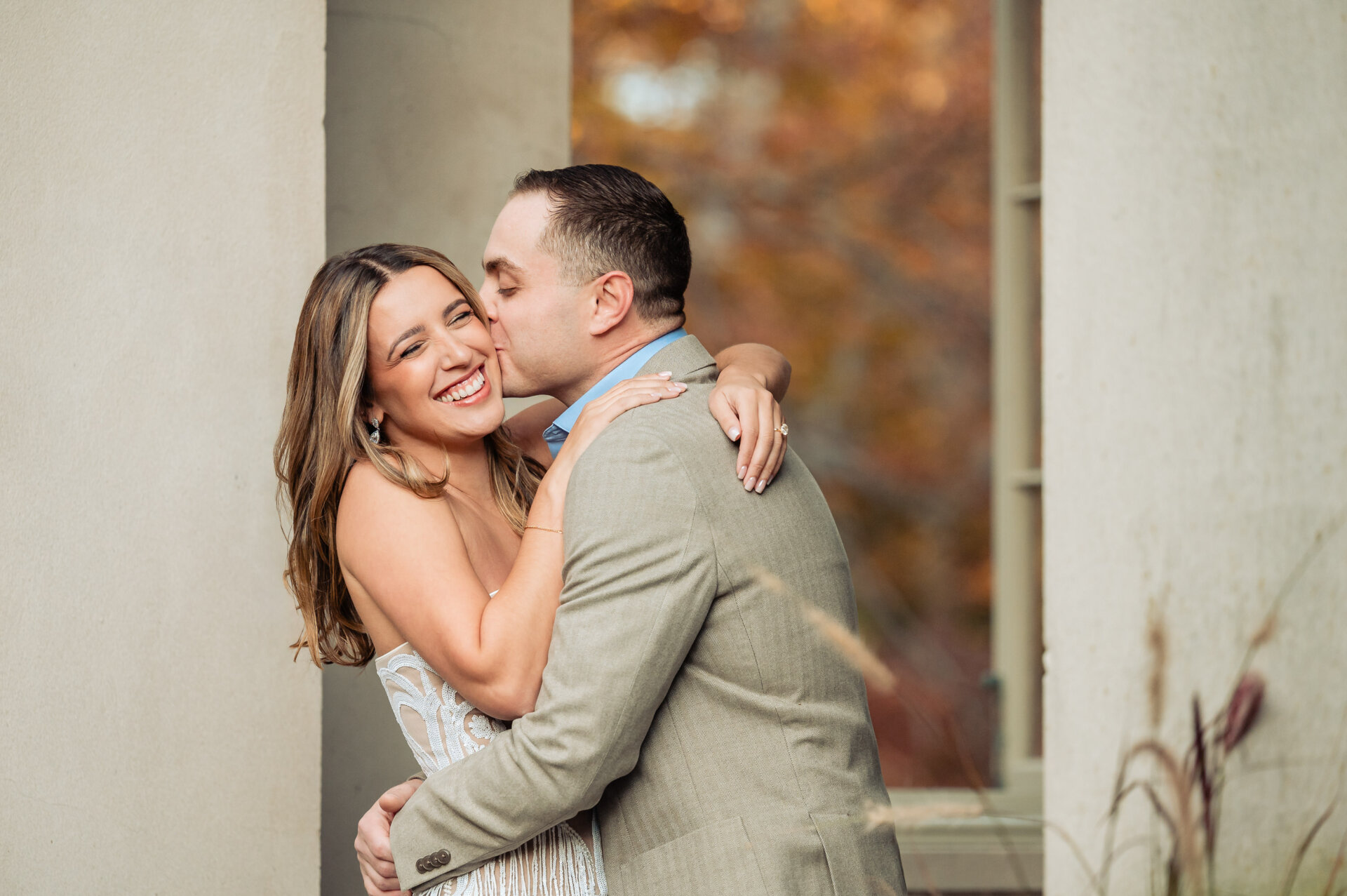 Couple embracing and smiling during an autumn engagement session at Winterthur.