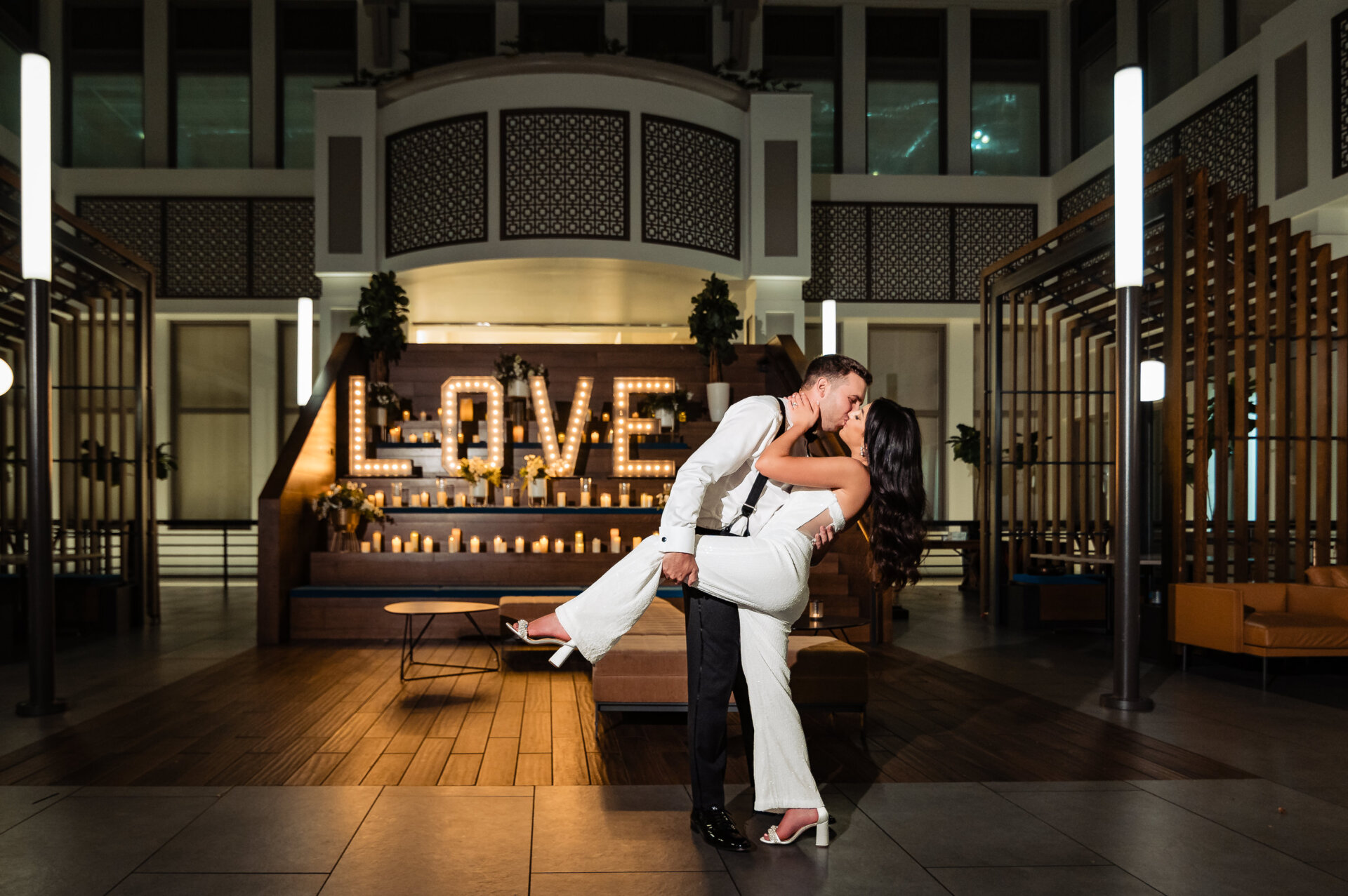 Bride and groom sharing a dramatic dip kiss in front of candlelit LOVE letters in the Crystal Tea Room