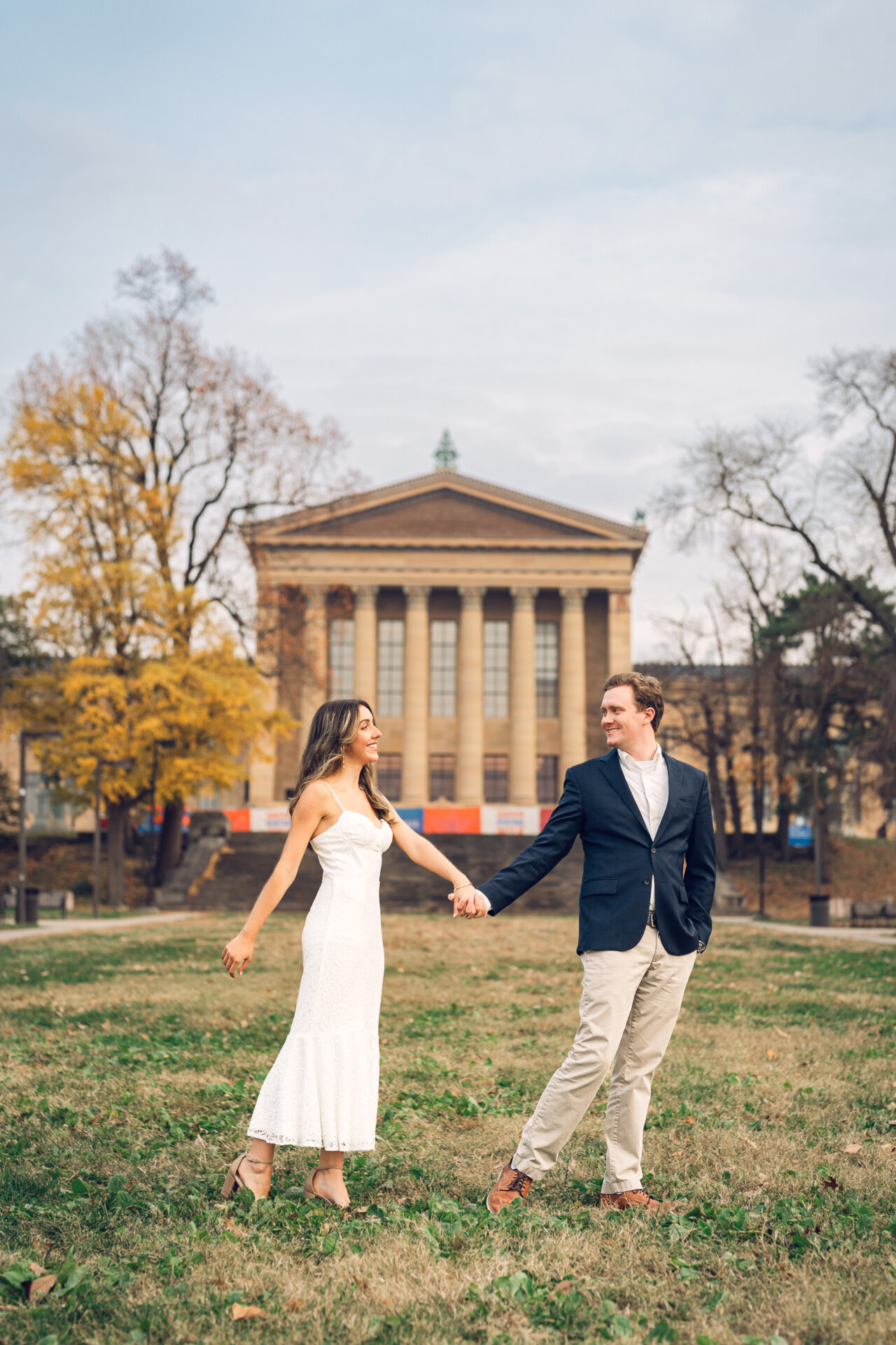 Couple holding hands while walking on the lawn near the Philadelphia Art Museum.
