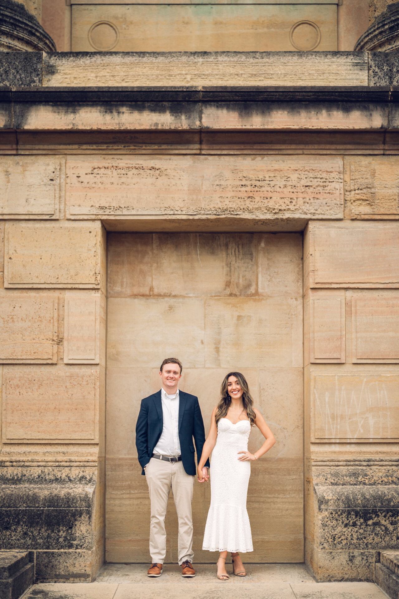 Engaged couple posing in front of a stone wall at Philadelphia Waterworks.