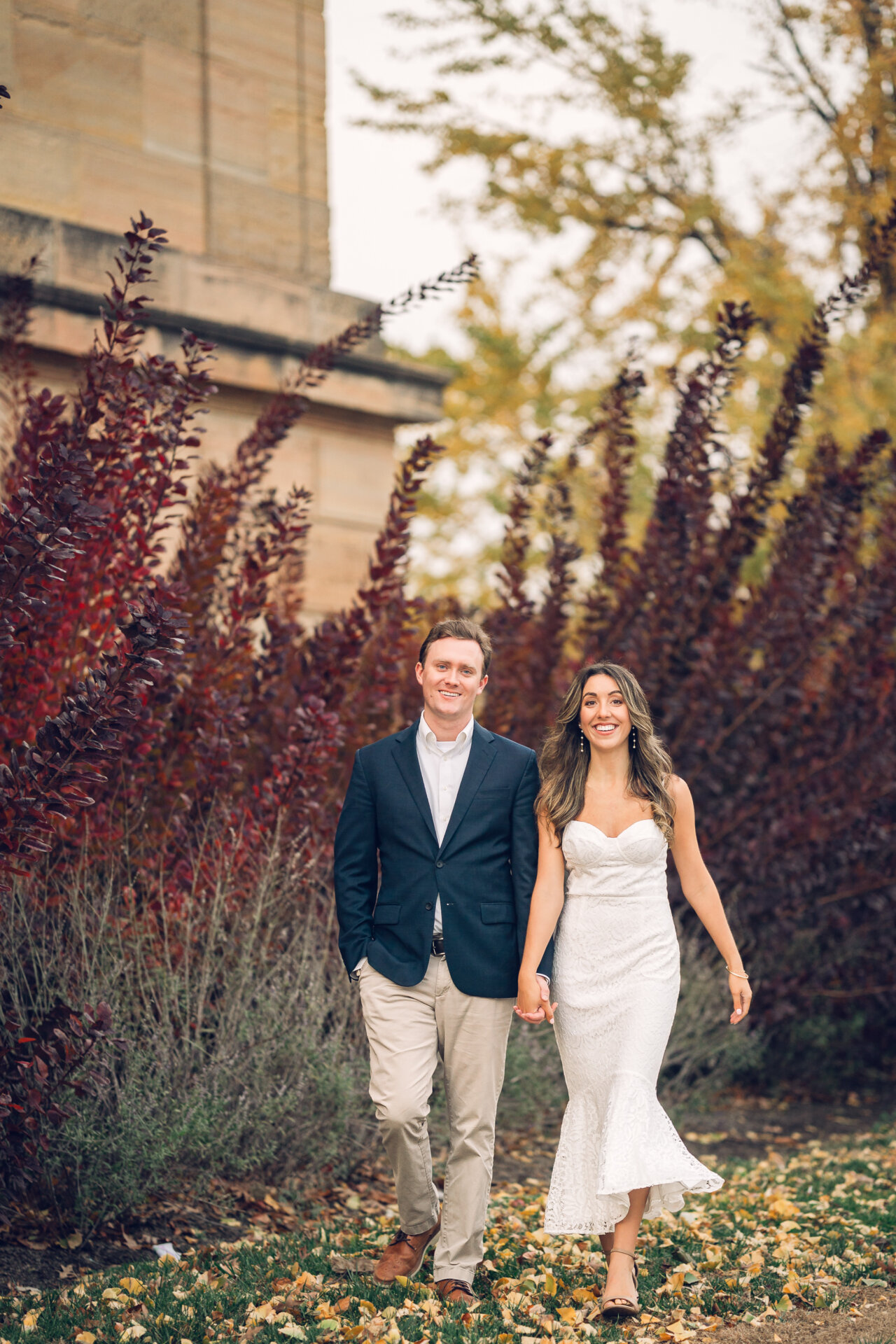 Engaged couple strolling together beside the Art Museum in autumn.