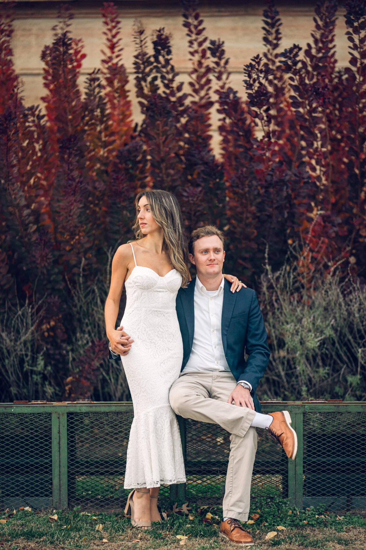 Engaged couple seated together against autumn foliage at the Art Museum.