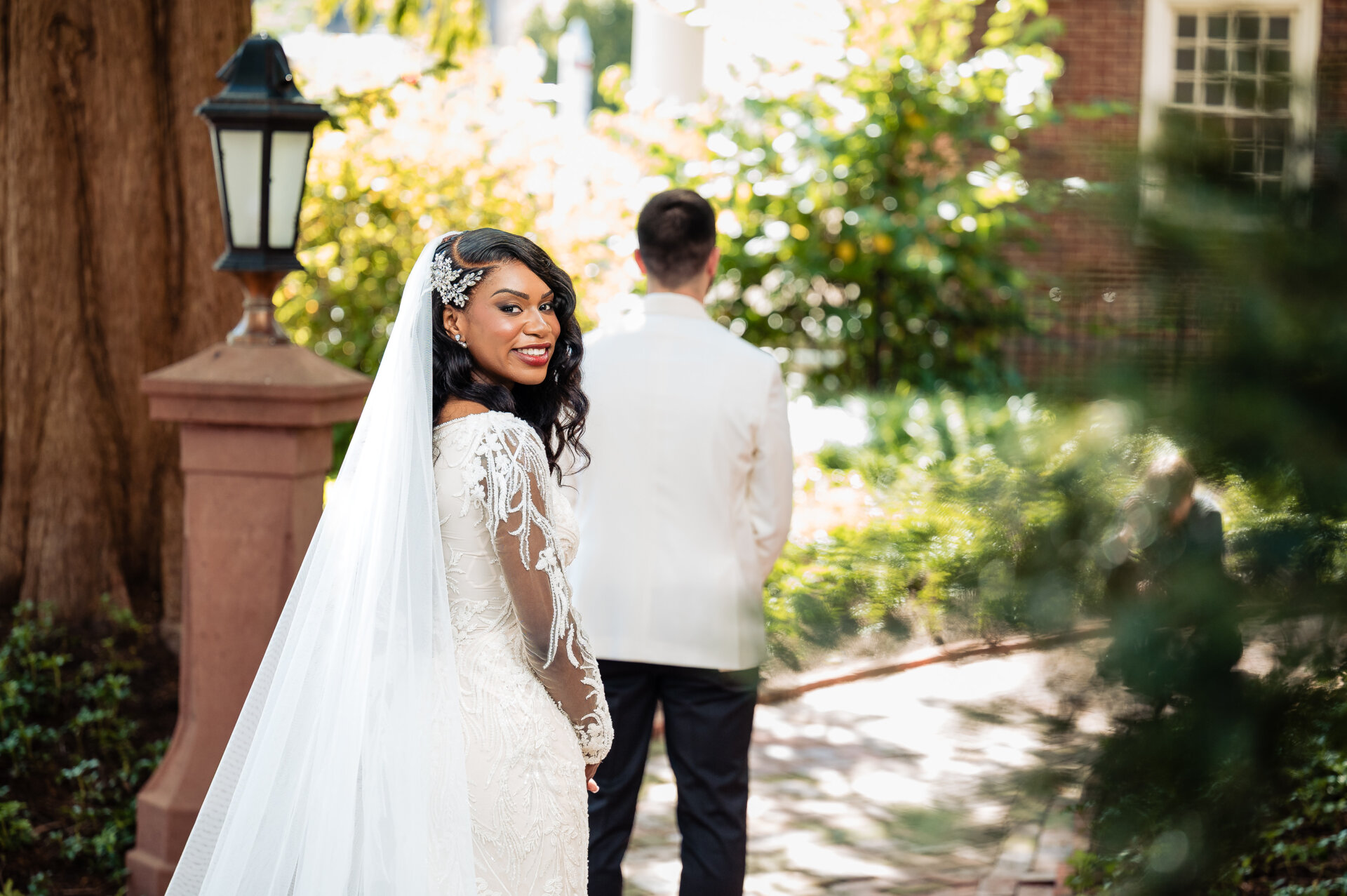 Bride and groom first look moment outdoors, bride looking back at groom in white dinner jacket surrounded by greenery