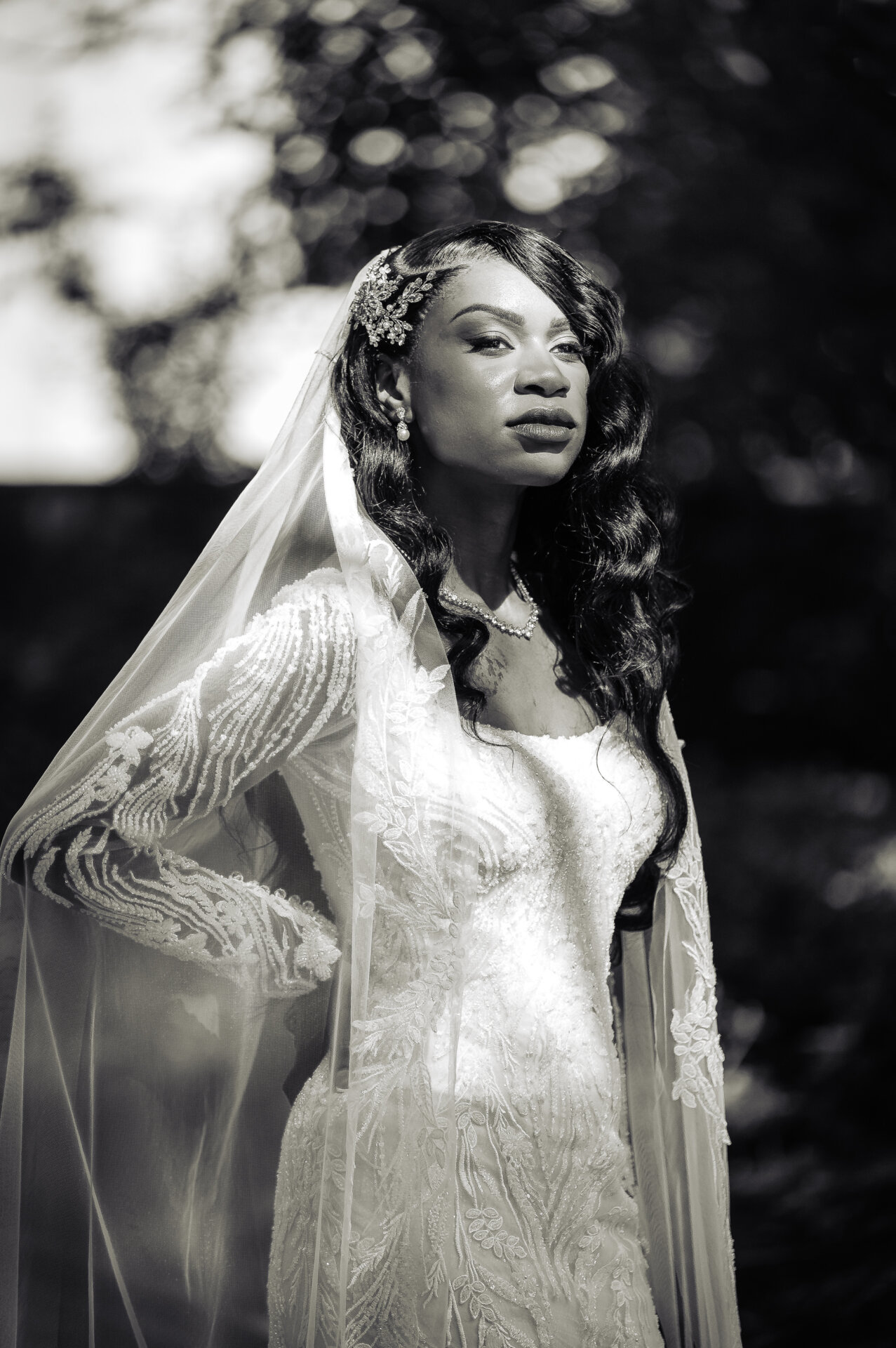 Black and white portrait of bride in lace long-sleeve wedding gown with veil in natural outdoor light