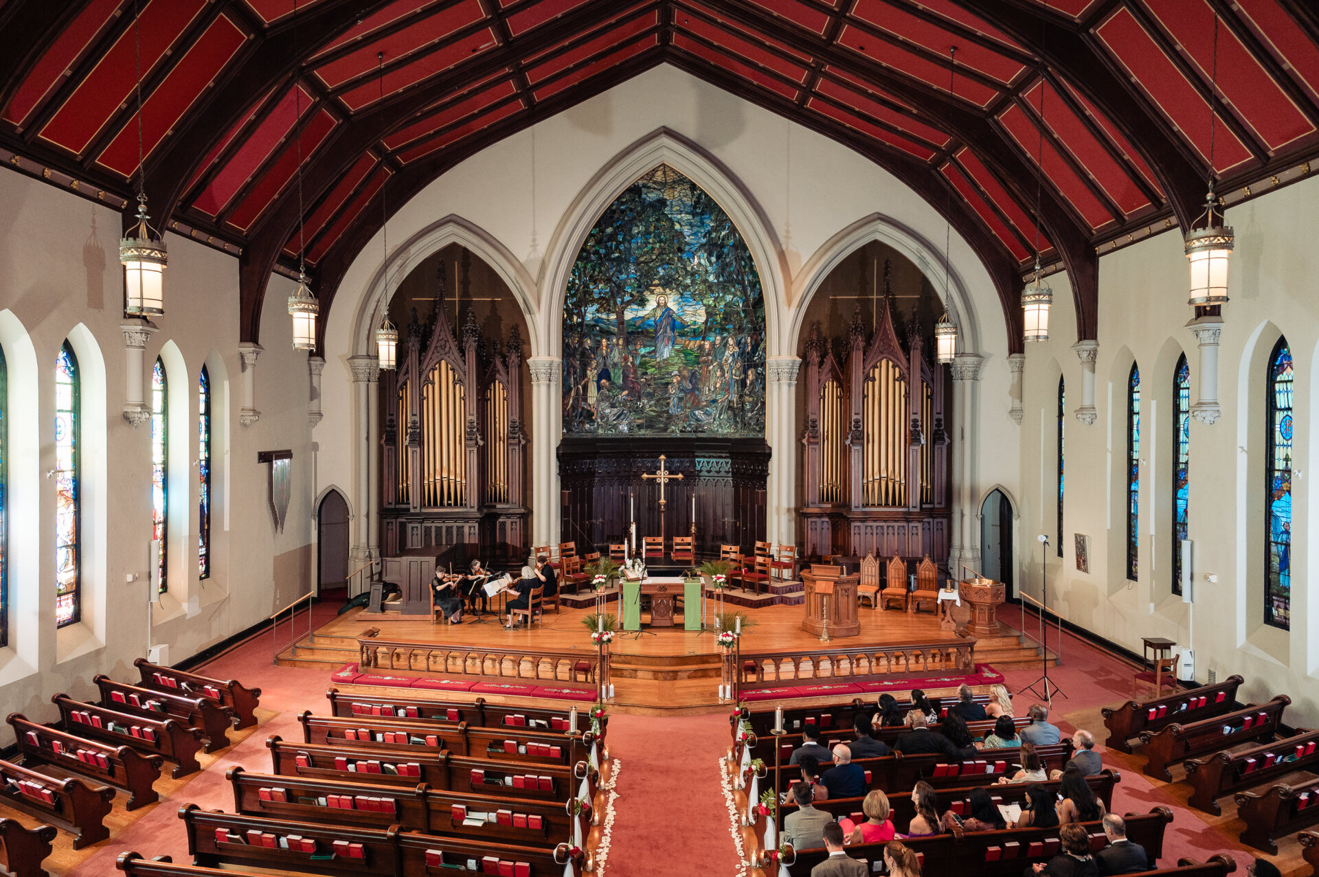 Wide view of a church wedding ceremony with the bride and groom at the altar surrounded by guests.
