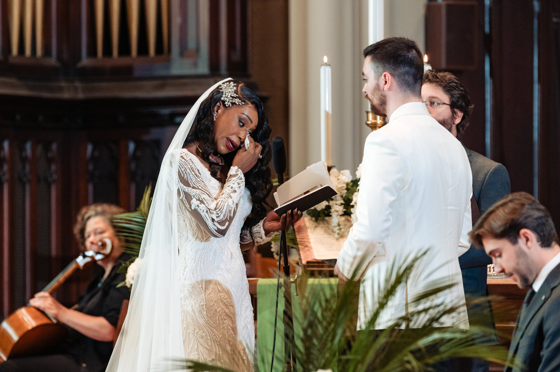 Bride reading vows during a church wedding ceremony as musicians perform in the background.