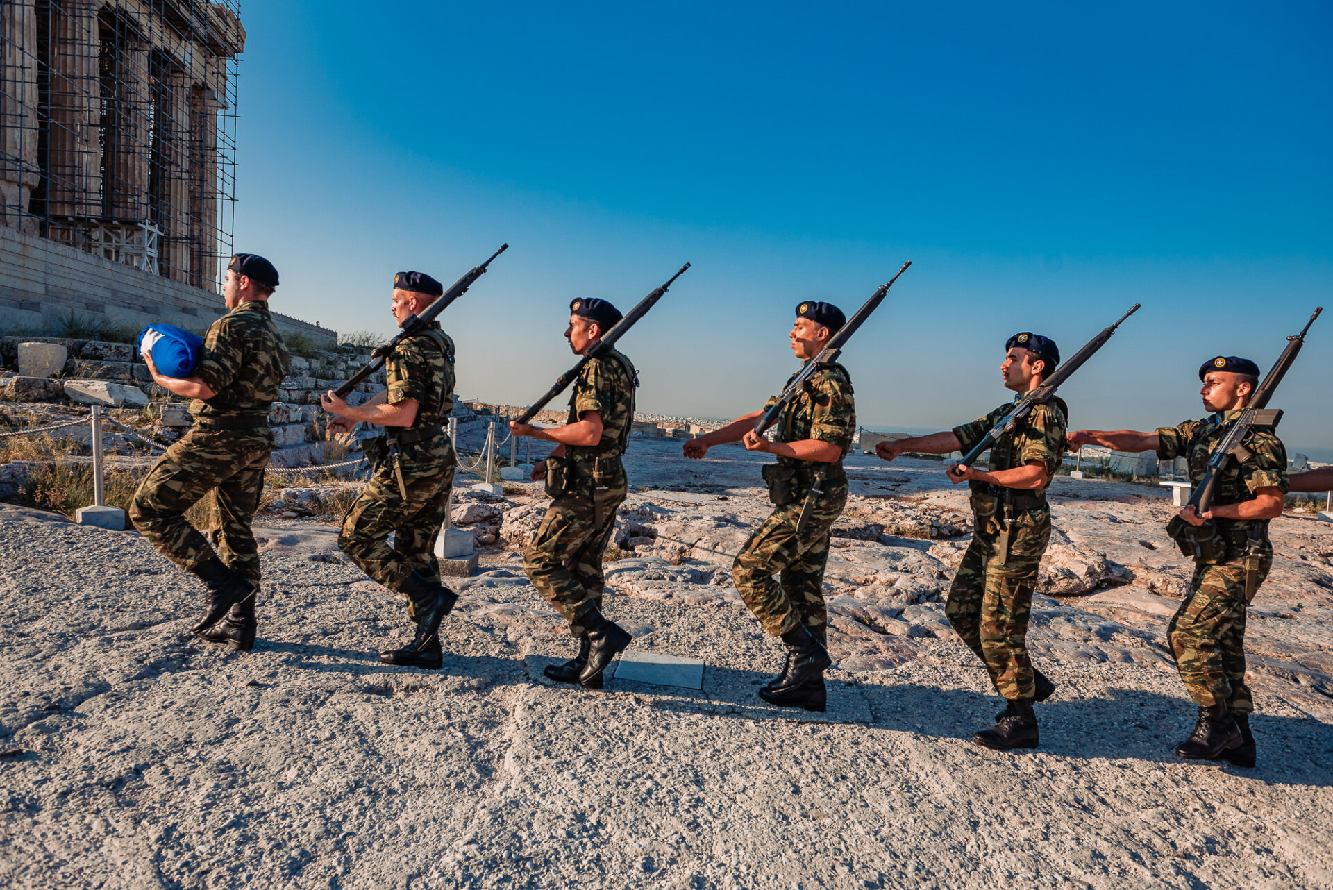 Greek army soldiers perform a ceremonial march past the Parthenon temple before raising the national flag on Acropolis Hill.