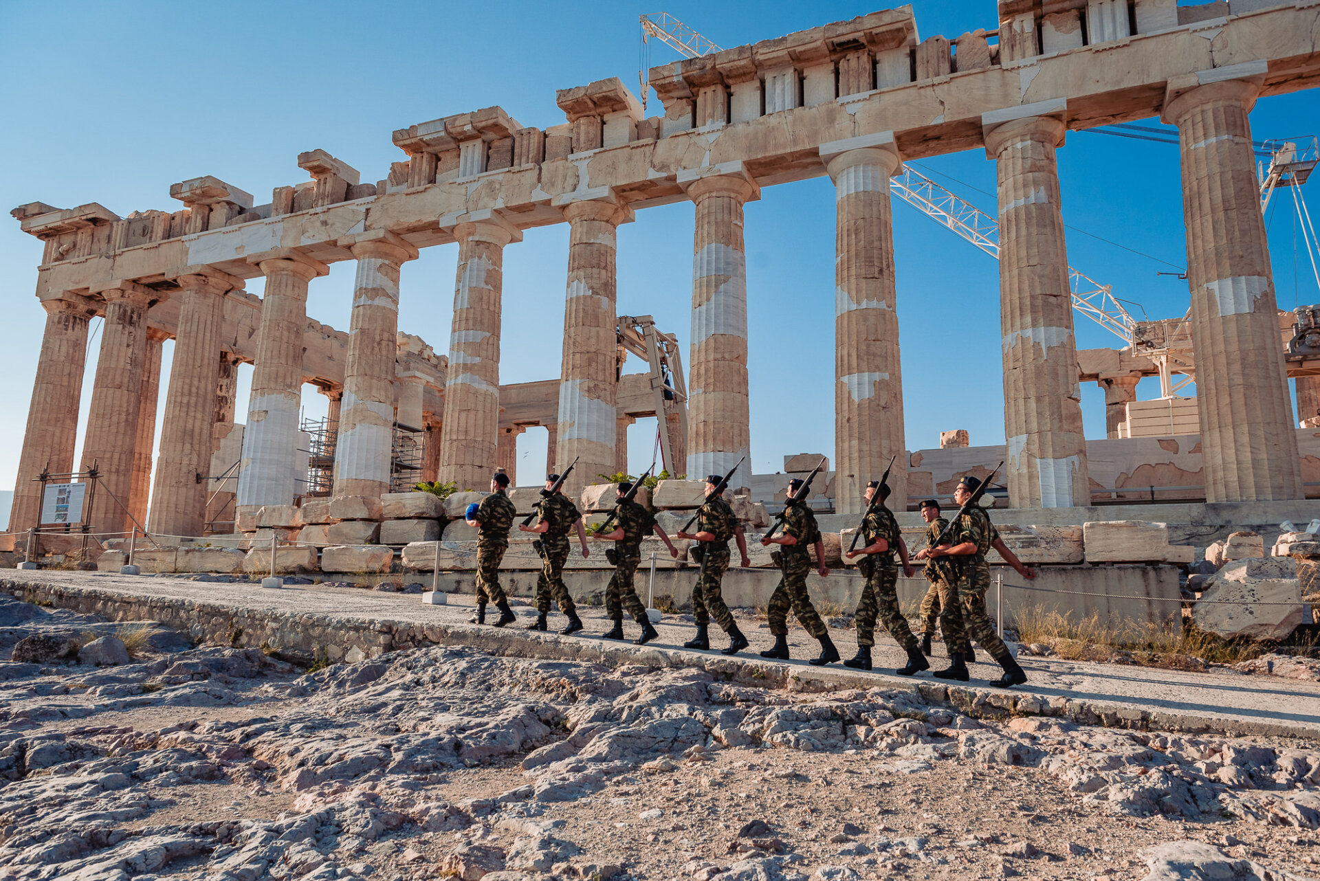 Greek army soldiers perform a ceremonial march past the Parthenon temple before raising the national flag on Acropolis Hill.