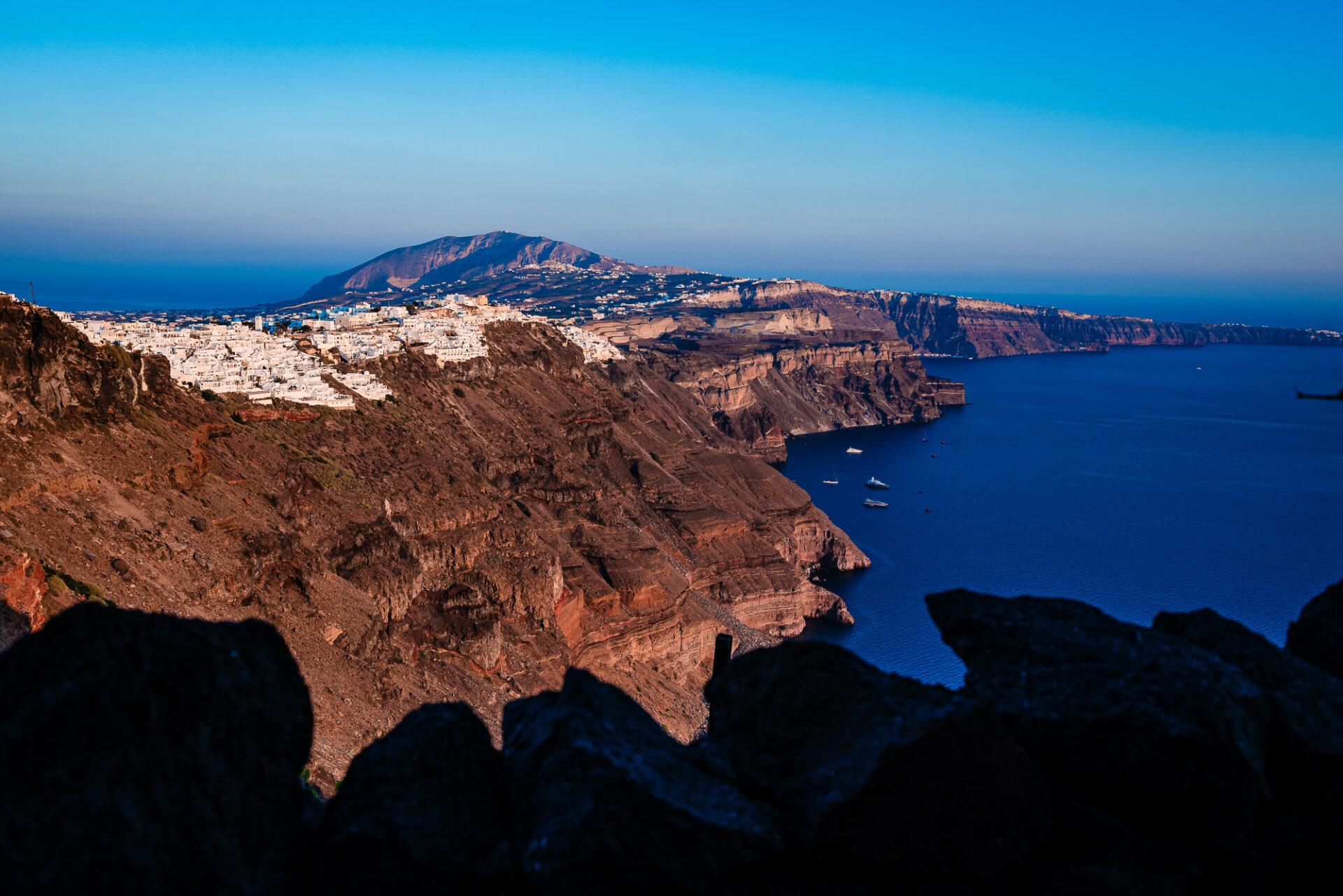 view of the Santorini caldera, a vast, crescent-shaped basin formed by a major volcanic eruption thousands of years ago.