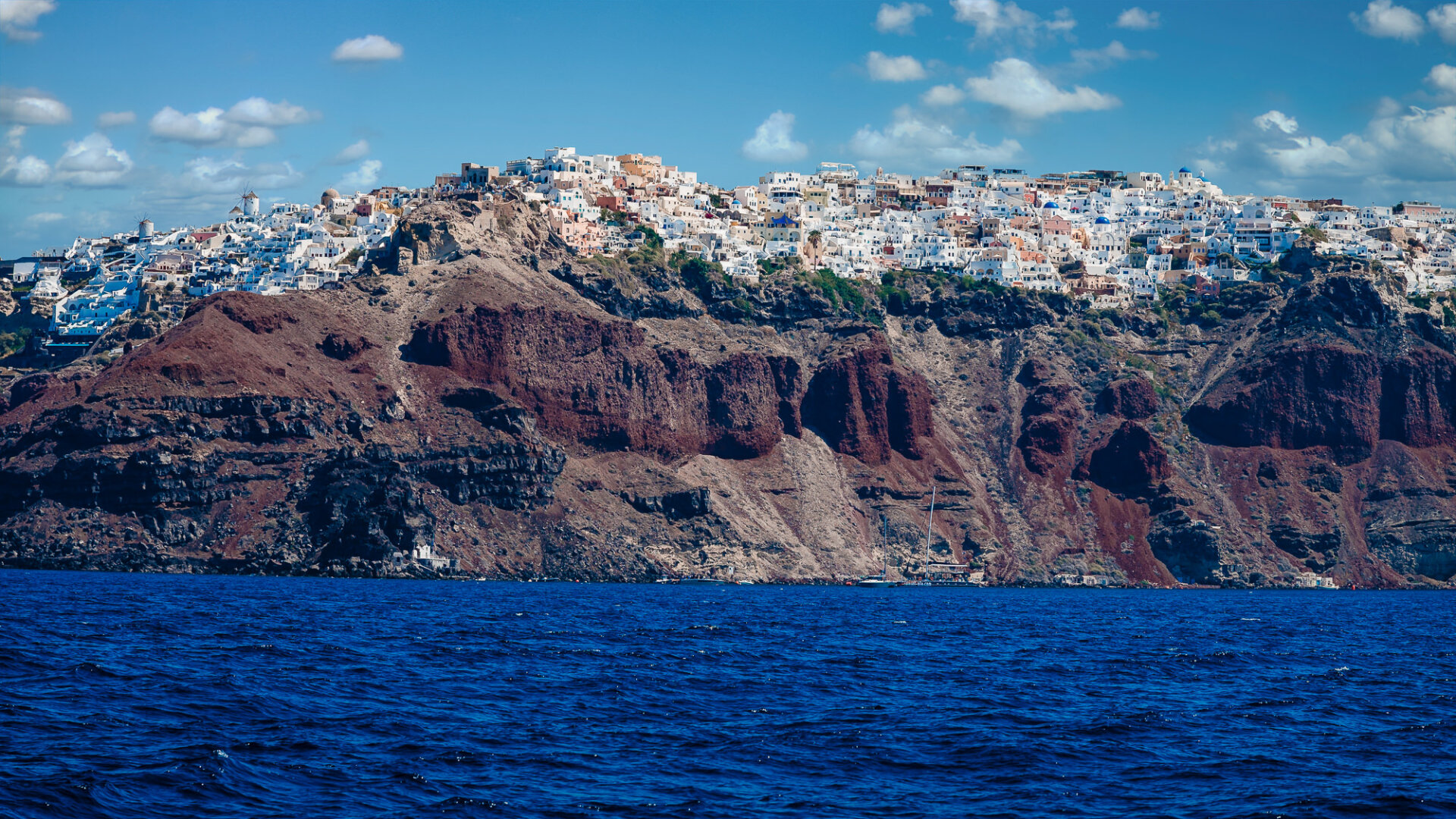 volcanic caldera cliffs of Santorini, Greece, specifically showcasing the town of Oia perched on the edge.