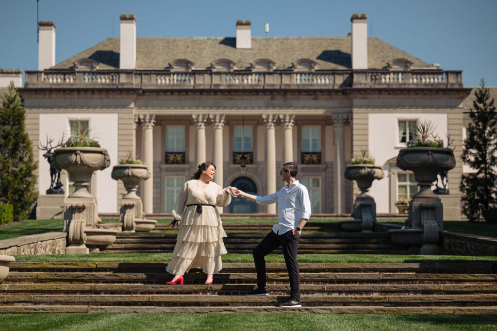 Playful hand in hand portrait in front of the nemours estate mansion