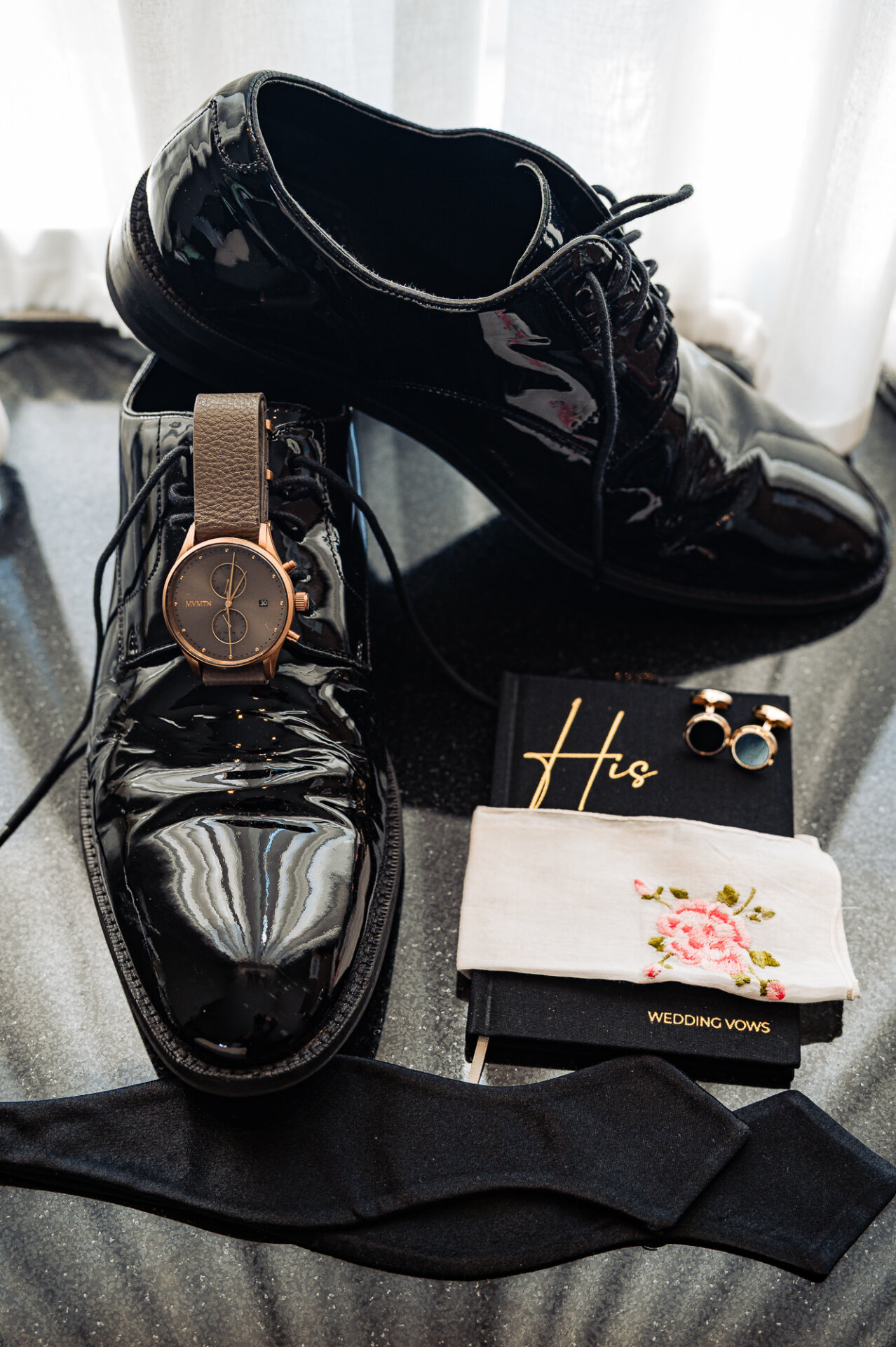 Groom wedding details featuring patent leather dress shoes, cufflinks, watch and handwritten vows
