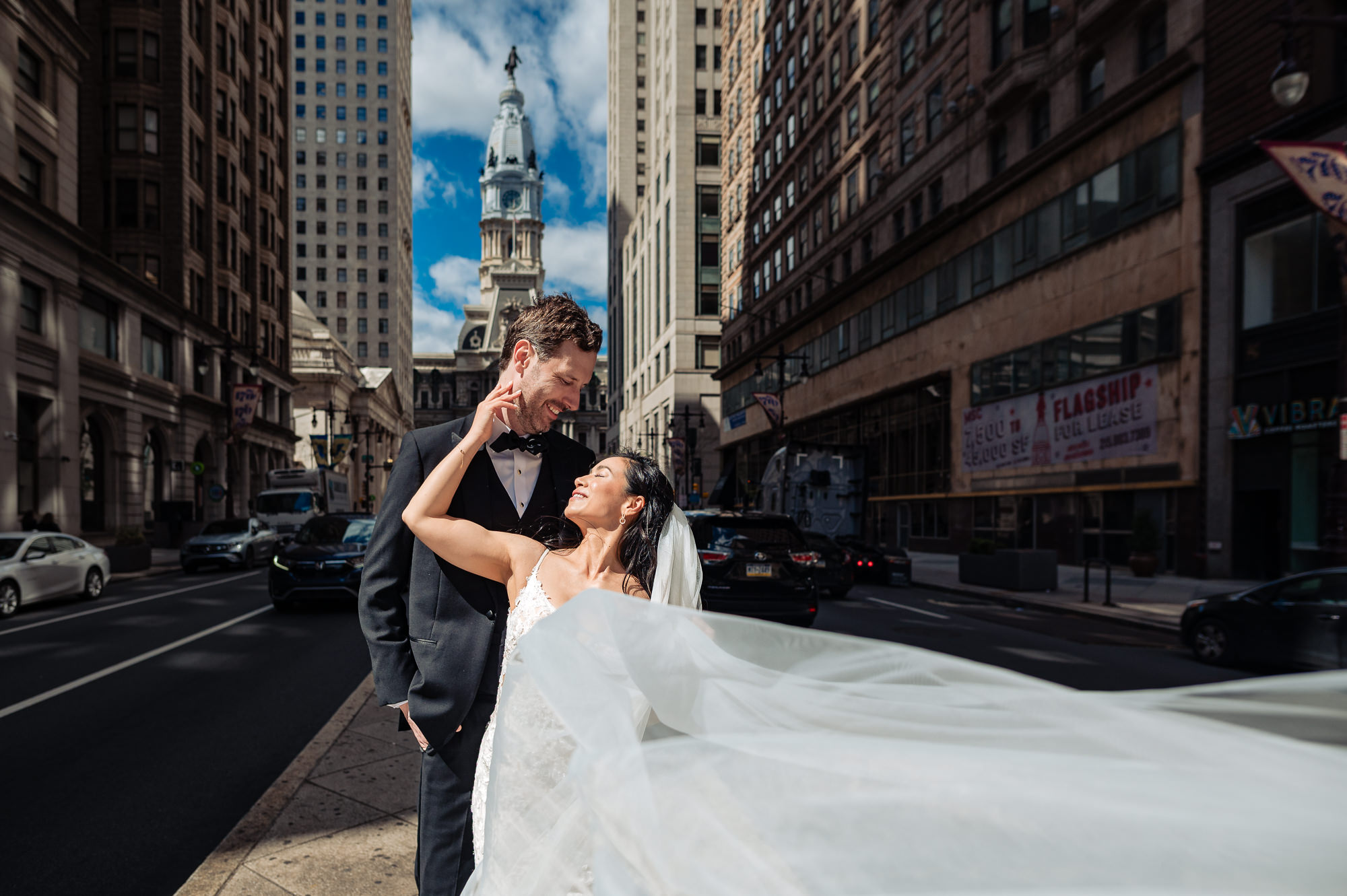 Playful downtown Philadelphia wedding portrait with a sweeping veil and city skyline views
