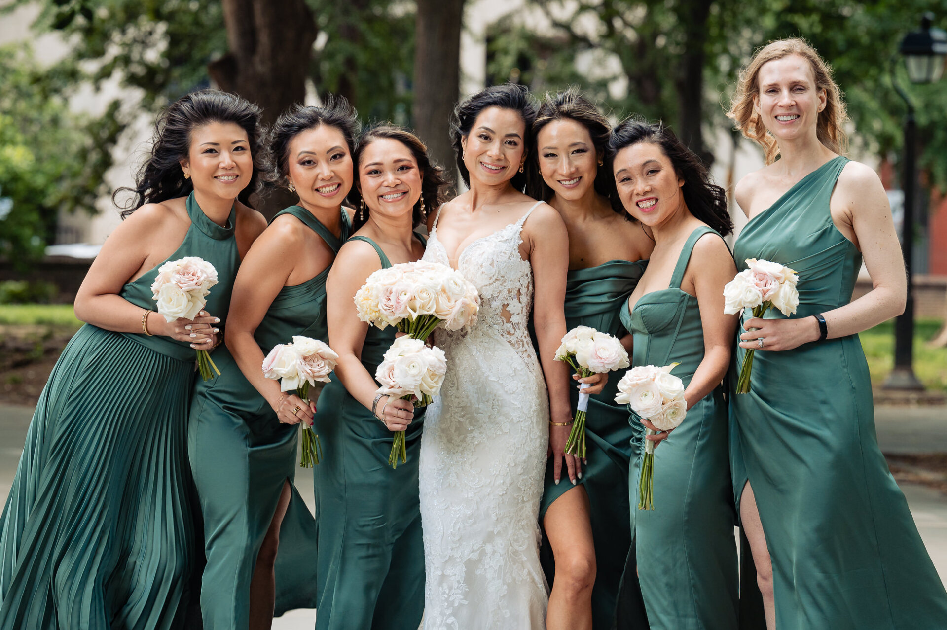 Bride surrounded by bridesmaids in sage green dresses during wedding portraits