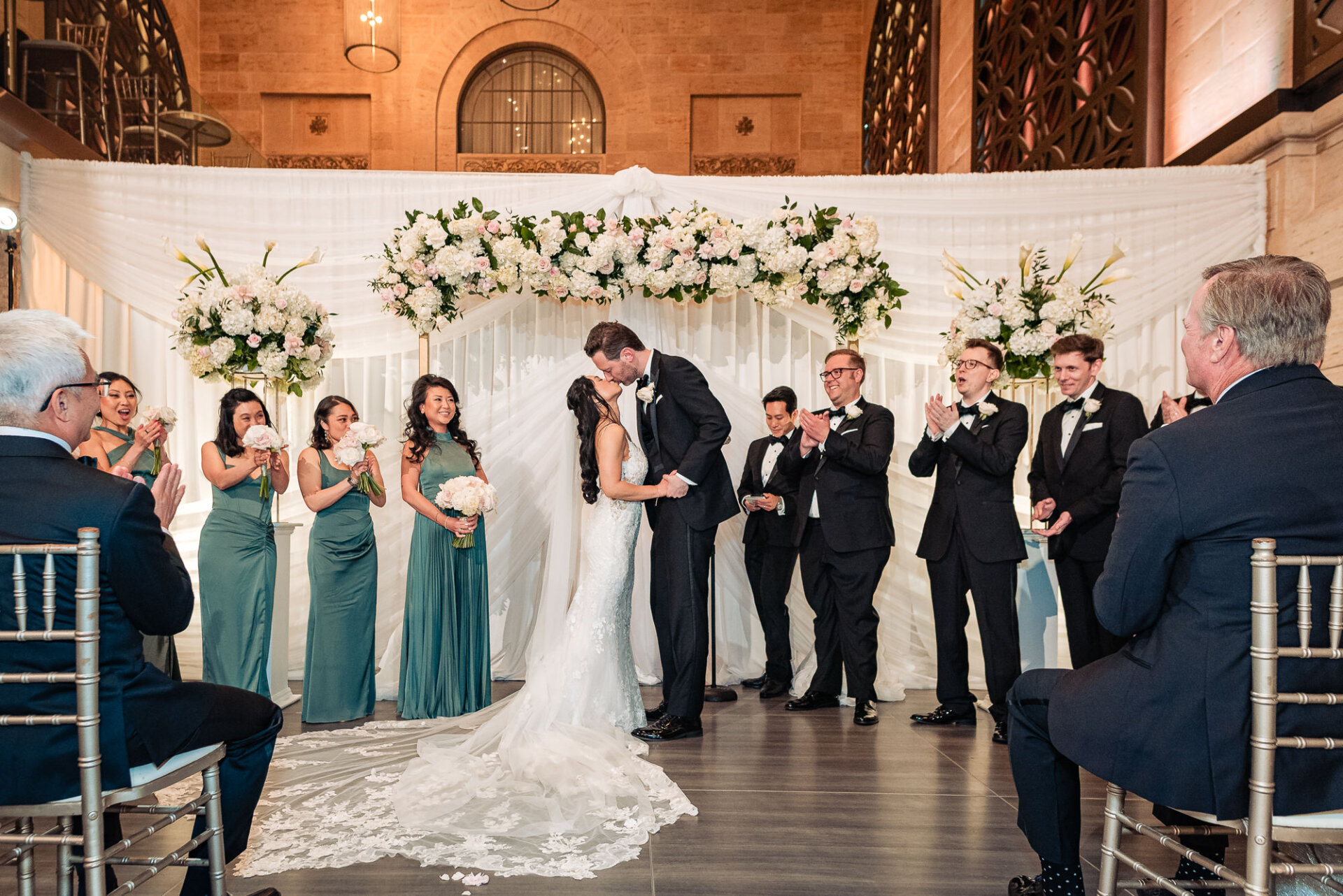 Kim and Greg share their first kiss beneath a floral ceremony backdrop at Union Trust